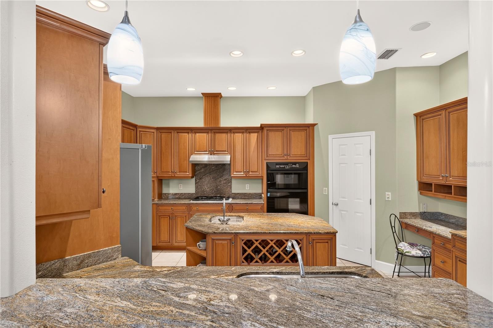 Kitchen with granite counters, extensive wood cabinetry, a large island, and built-in double ovens.