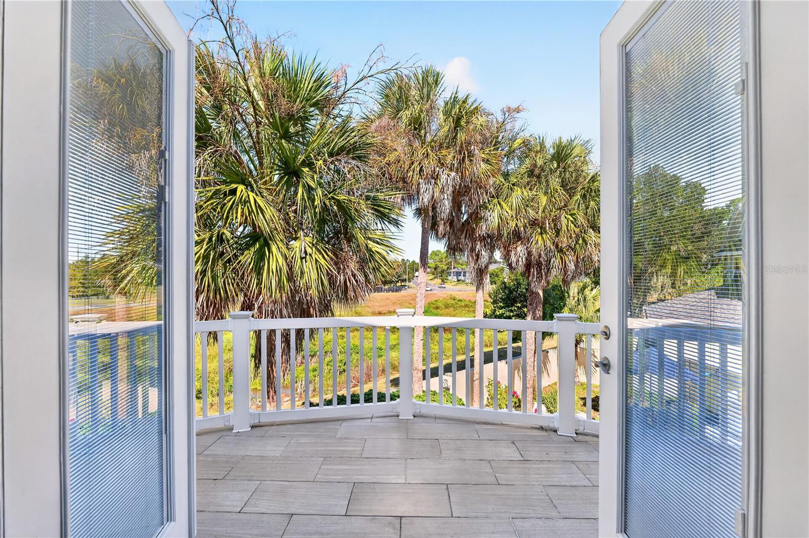 Tiled balcony with white railing and palm trees beyond.