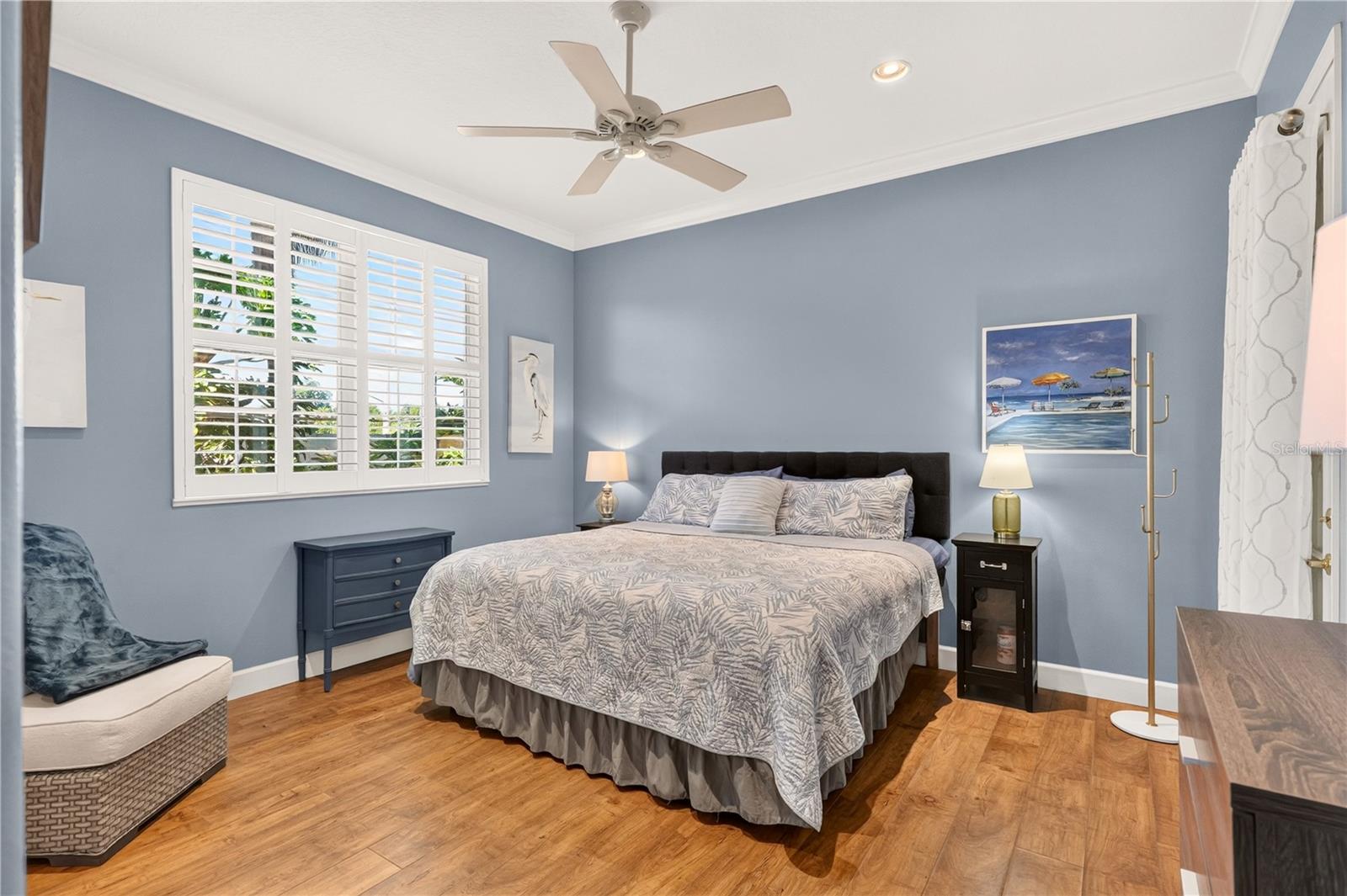 Bedroom with a king bed, blue-gray walls, and white plantation shutters.