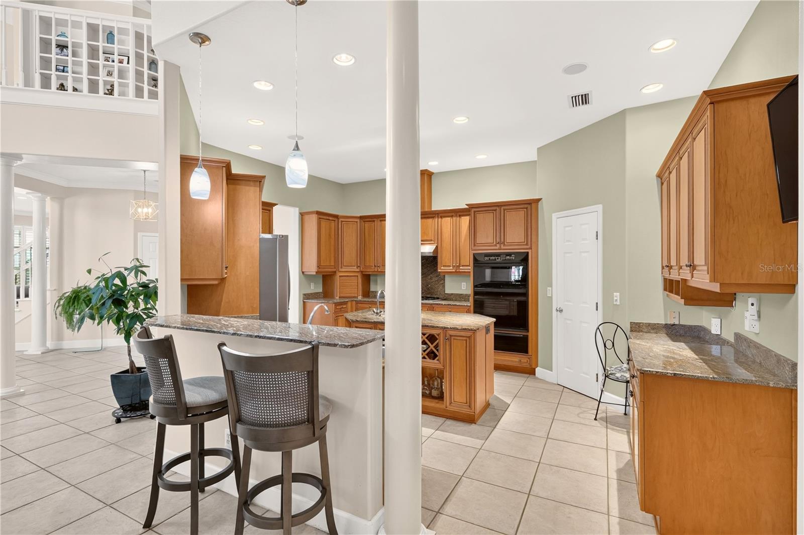 Spacious kitchen with wood cabinetry, granite counters, a central island, and two bar stools.