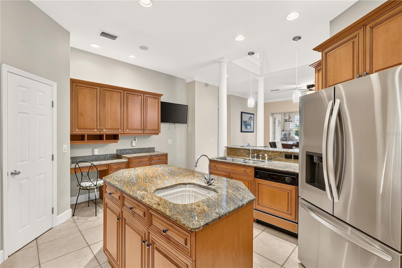 Kitchen with a granite-topped island, warm wood cabinets, and stainless steel appliances.