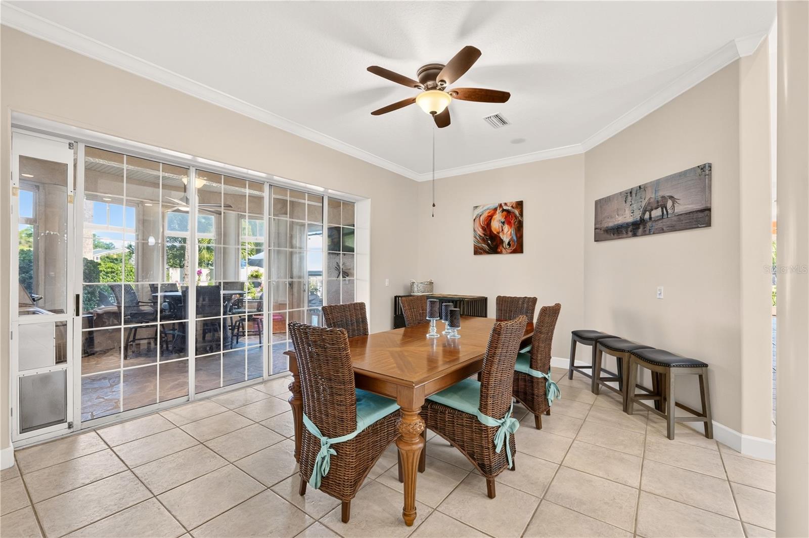 Dining room with wicker chairs, tiled floors, and sliding glass doors opening to a covered patio.