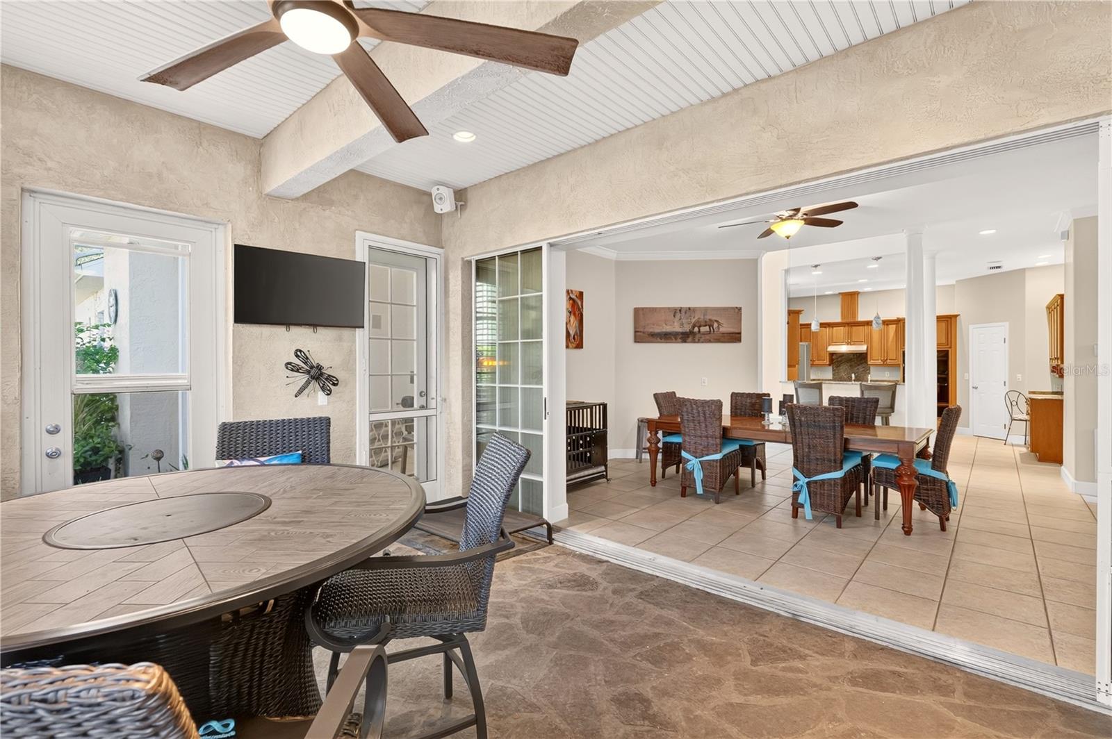 Covered patio with wicker dining set opens to an indoor dining area and kitchen.