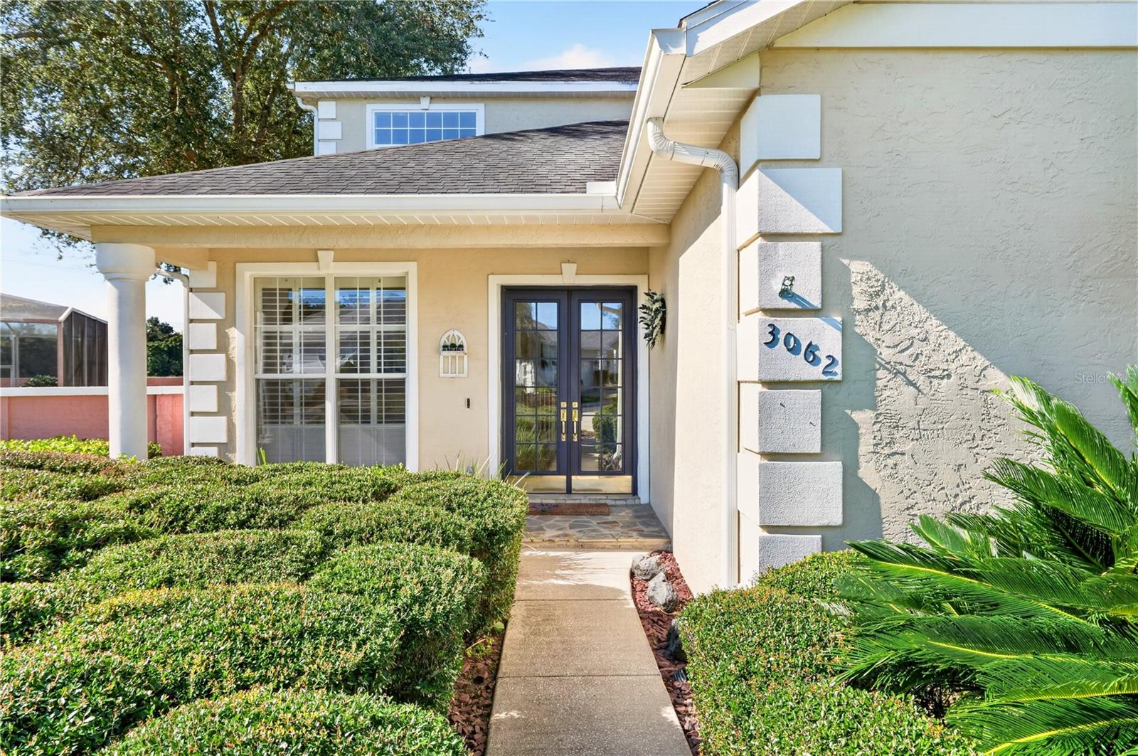 Home entrance with dark double doors, clipped hedges, and the number 3062 beside the door.