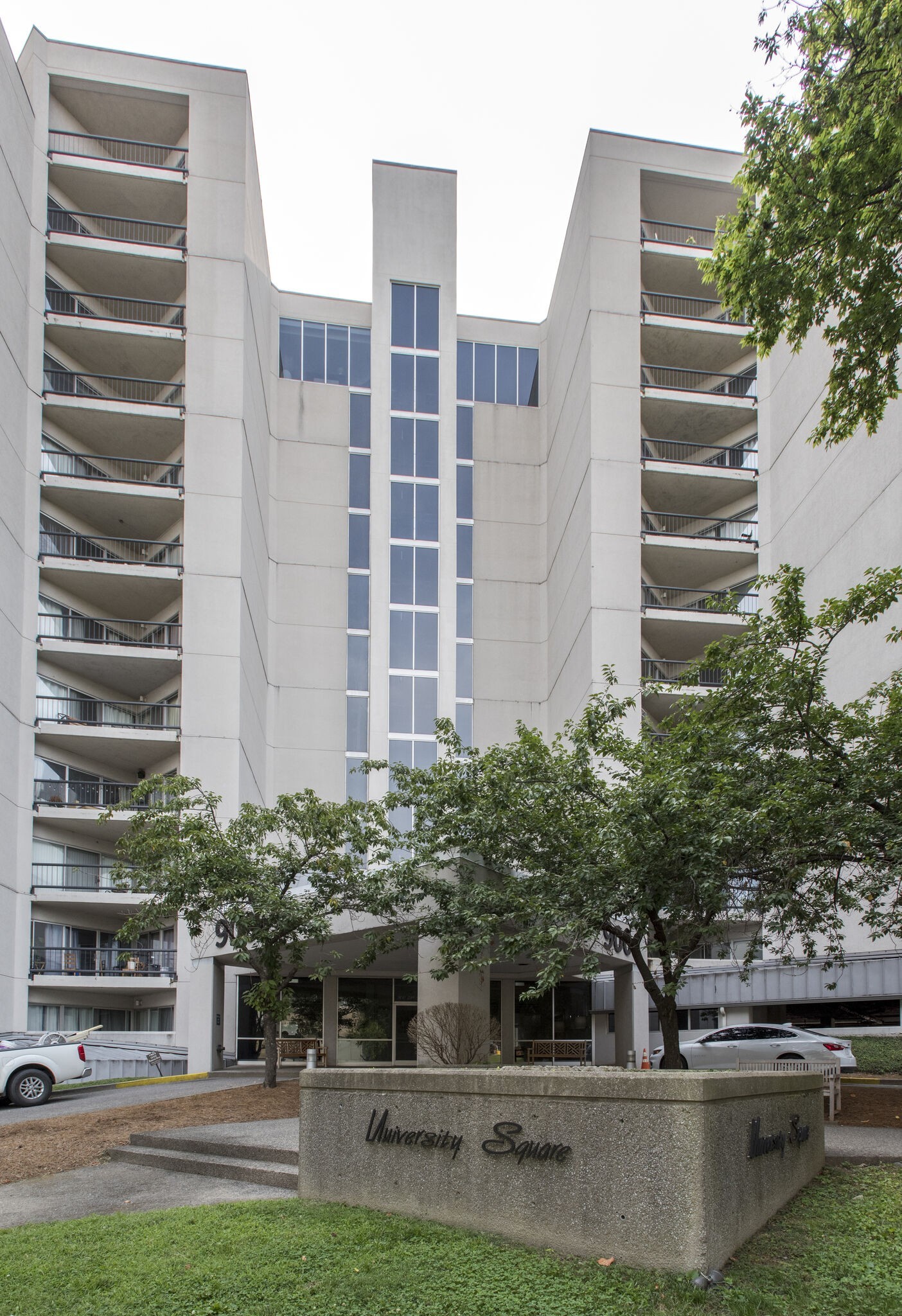 University Square condominium tower with stacked balconies and a landscaped entrance sign.
