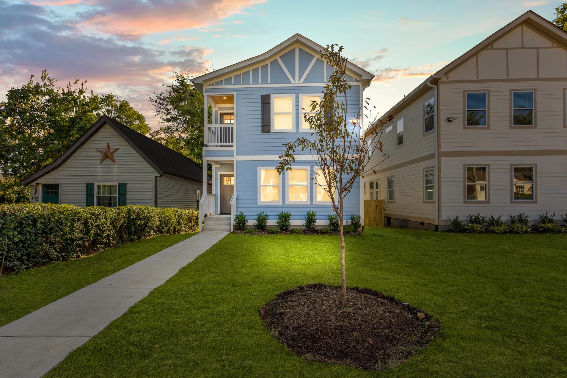 Blue two-story house with white trim and a front walkway at dusk.