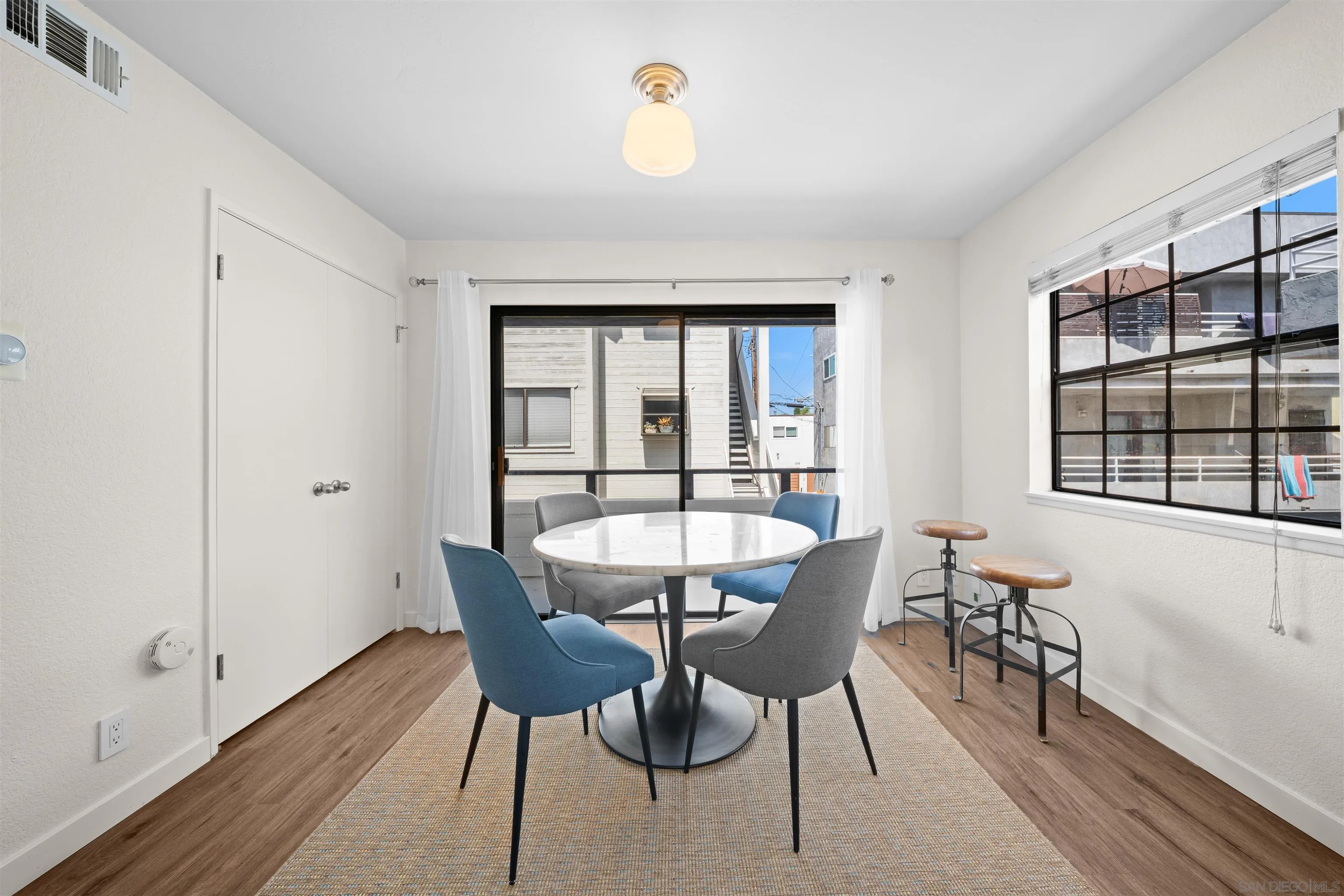 Dining area with a round table and four chairs beside sliding glass doors.
