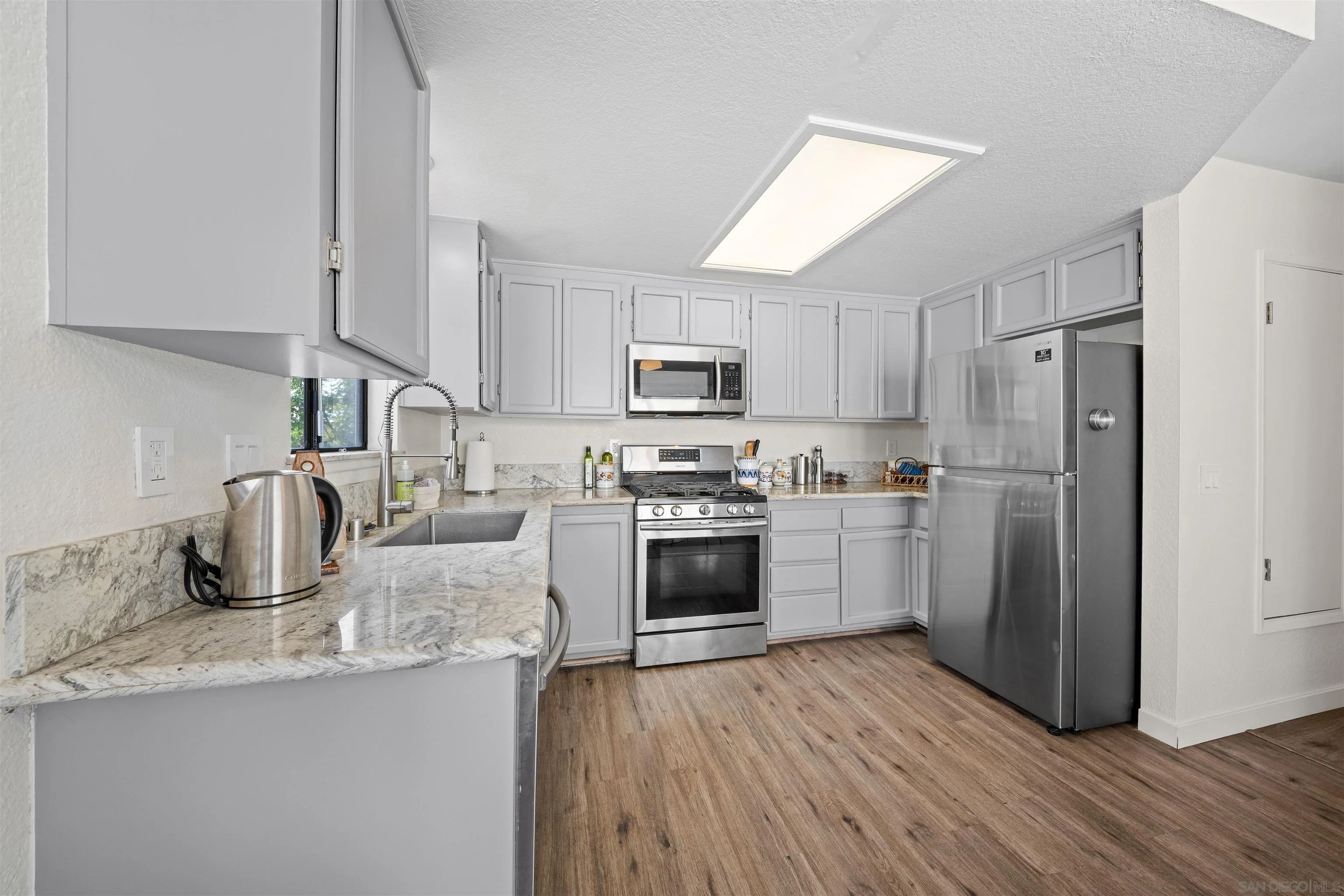 Kitchen with gray cabinets, marble-look counters, and stainless steel appliances.