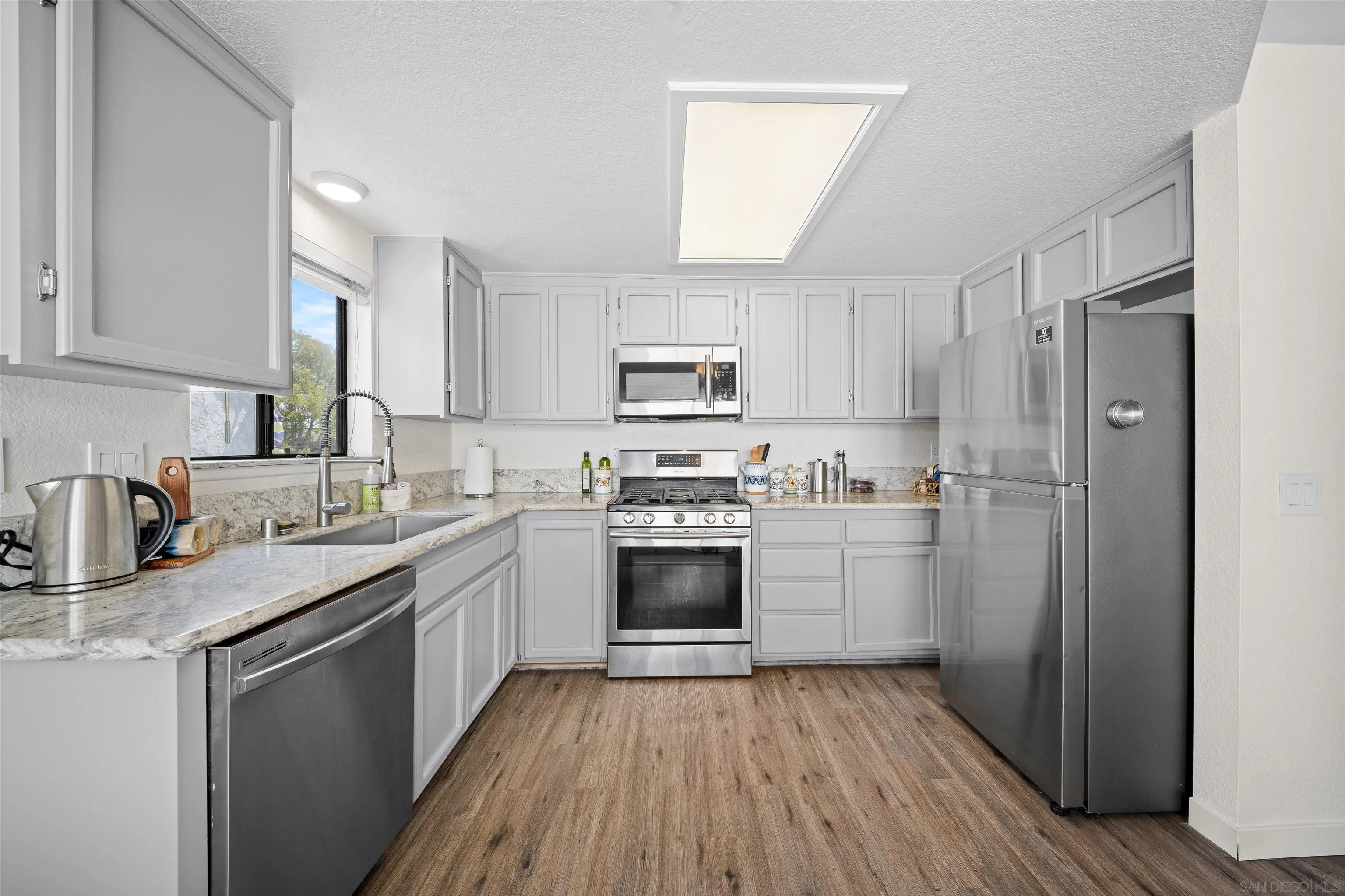 Kitchen with white cabinets, marble-look counters, and stainless steel appliances.