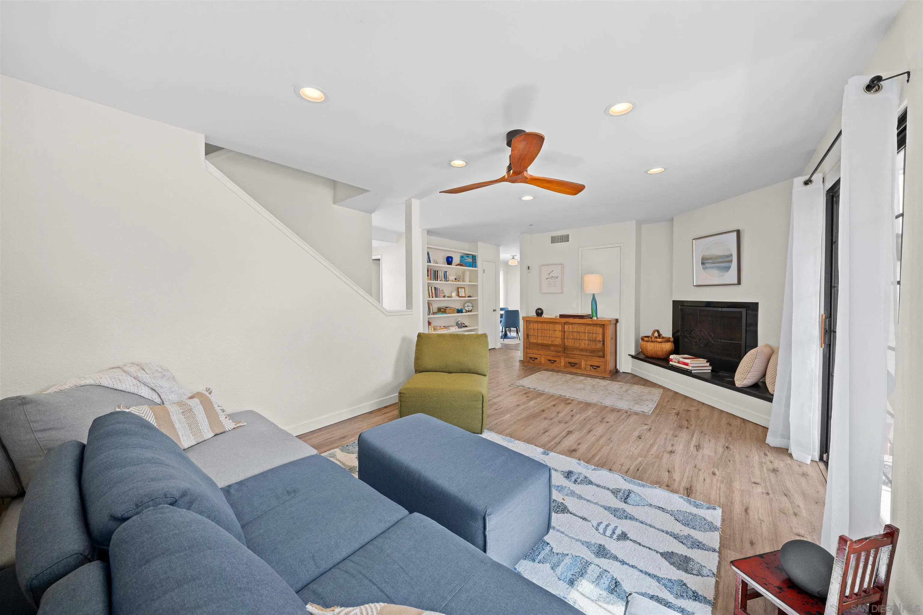 Living room with a gray sectional, wood-burning fireplace, and built-in bookshelves.