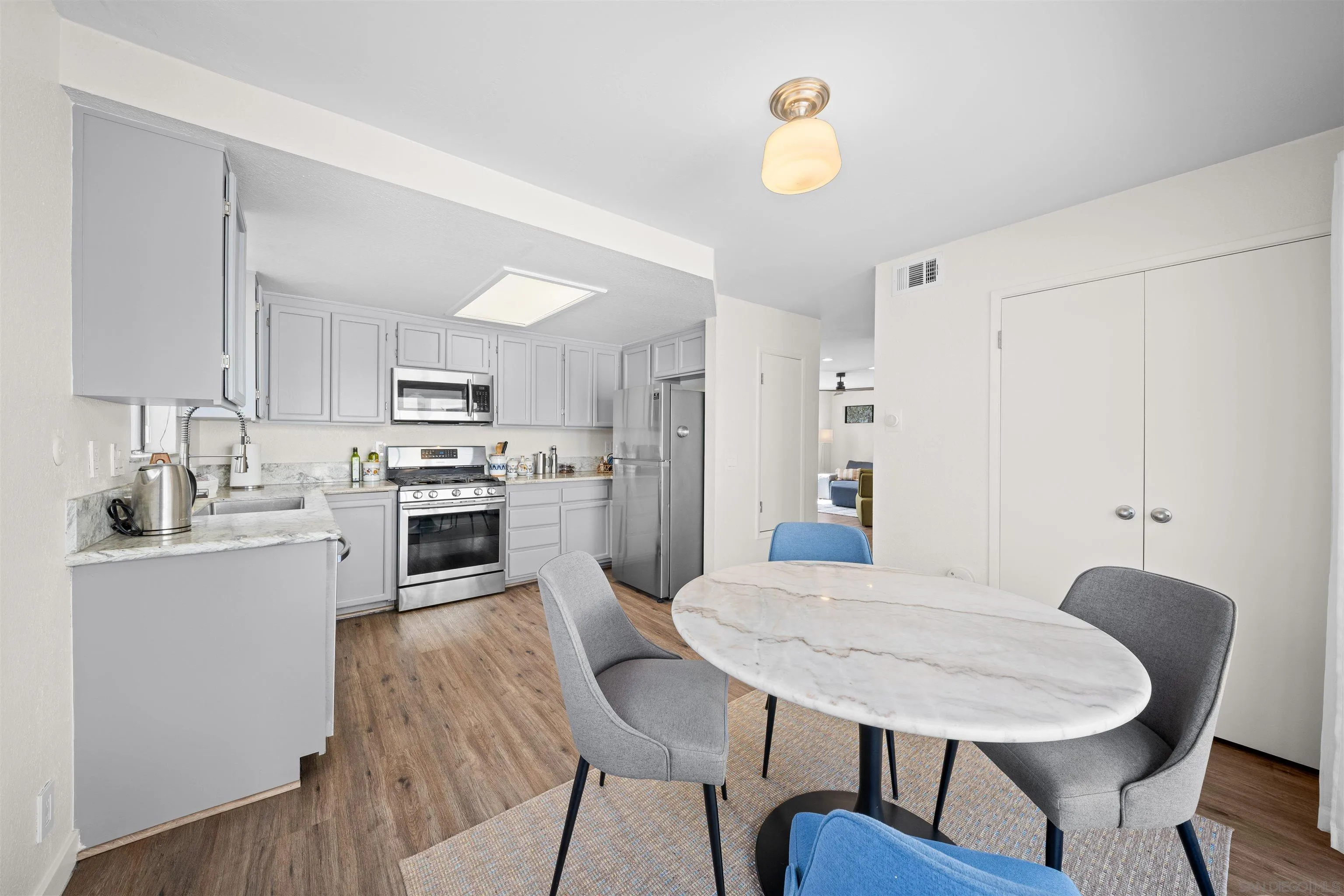 Kitchen and dining area with gray cabinets, stainless steel appliances, and an oval marble-look table.