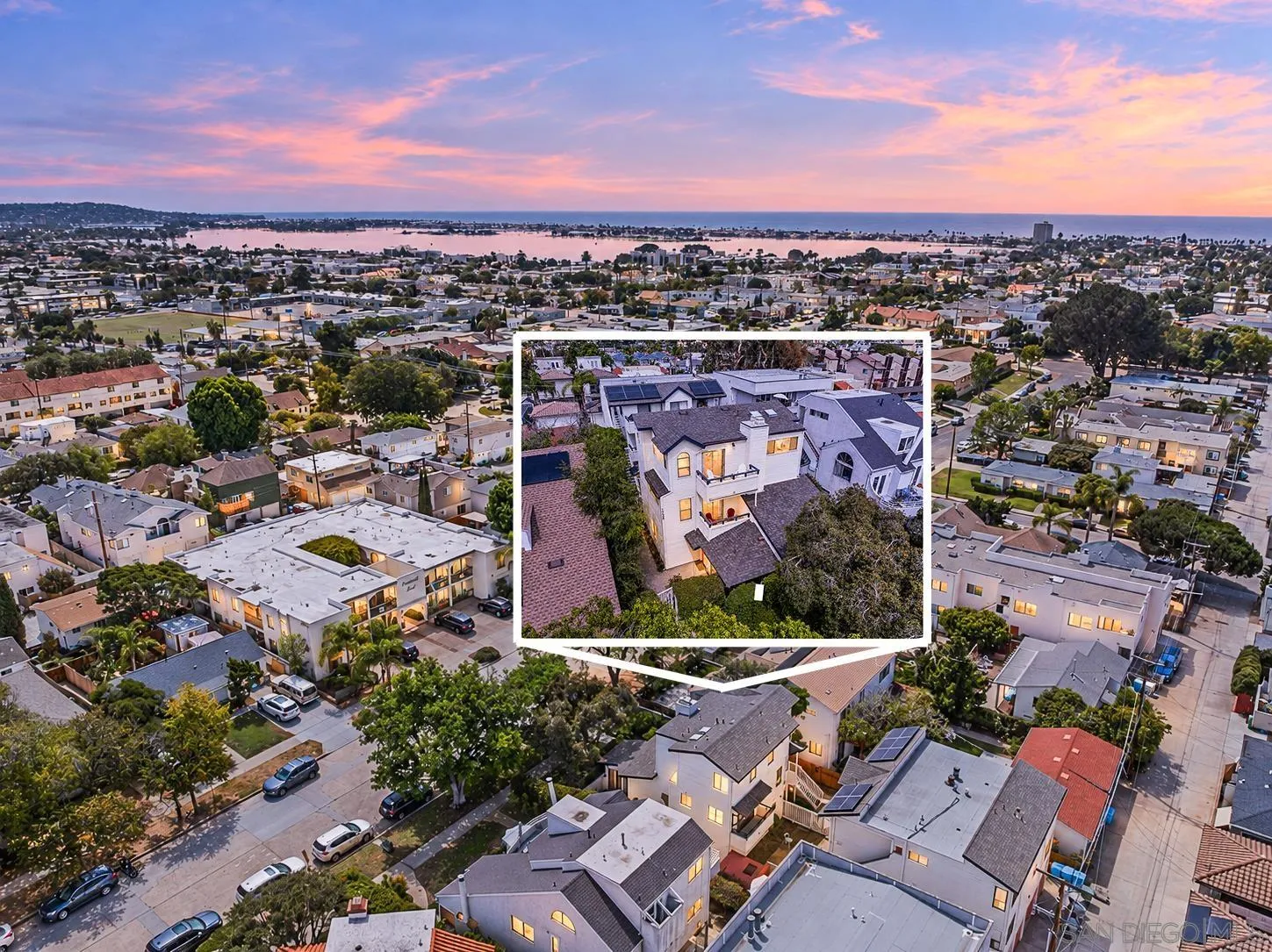 Aerial neighborhood view at dusk, with a white-outlined inset highlighting a multi-story home near the bay.