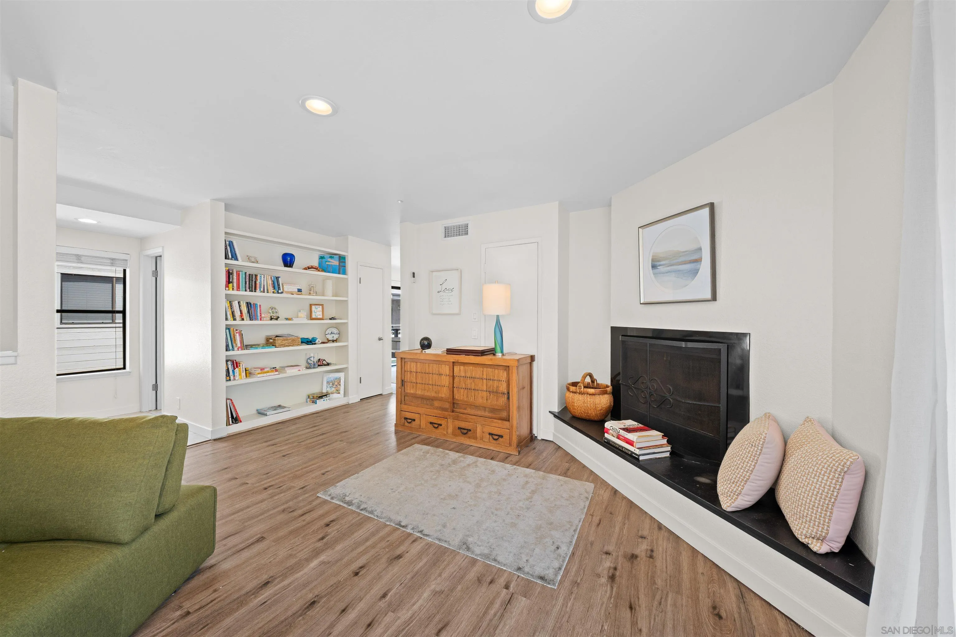 Furnished living room with a black fireplace, built-in bookshelves, and wood-look flooring.