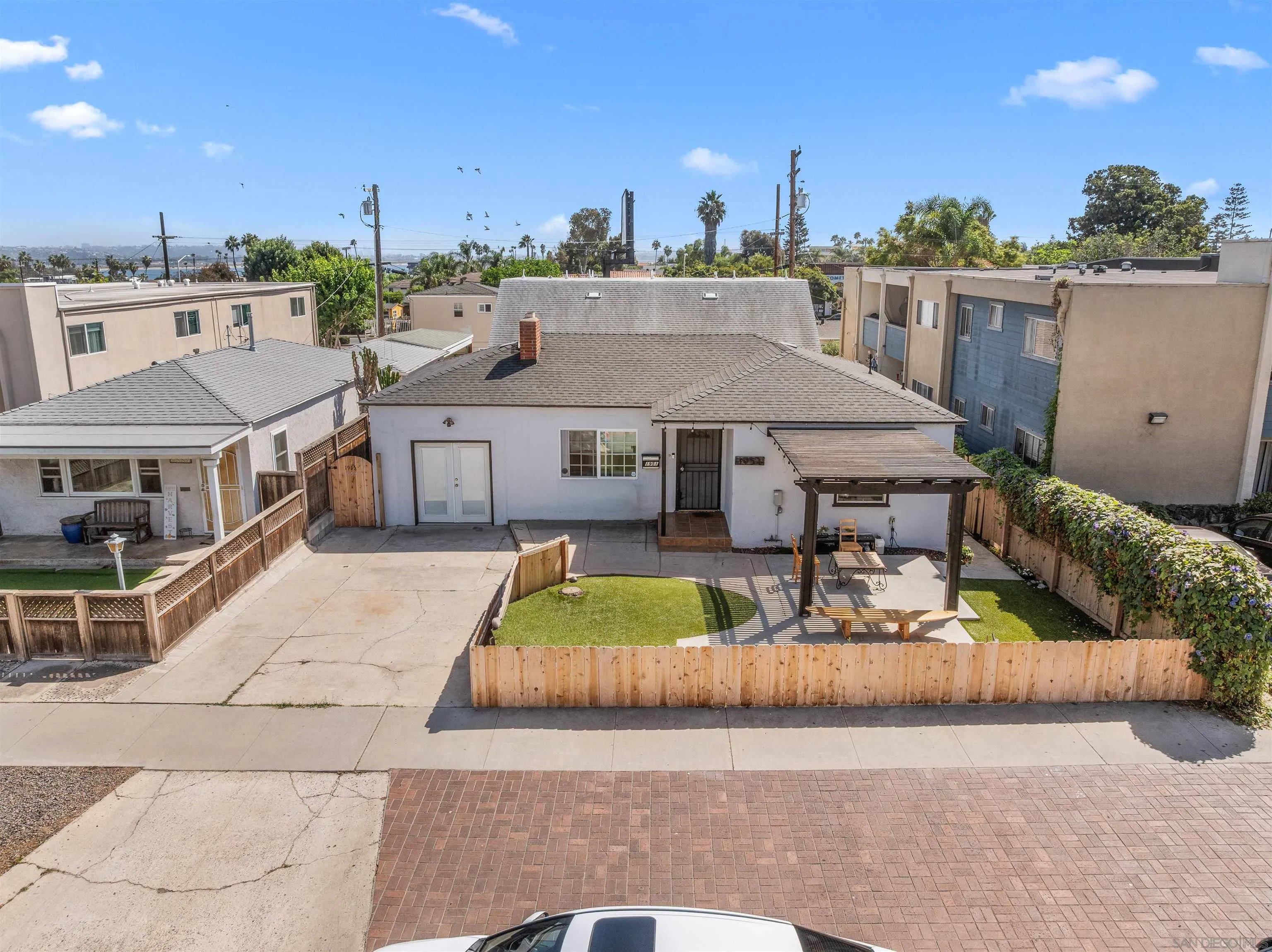 Rear exterior with a fenced lawn, pergola-covered patio, and neighboring homes.