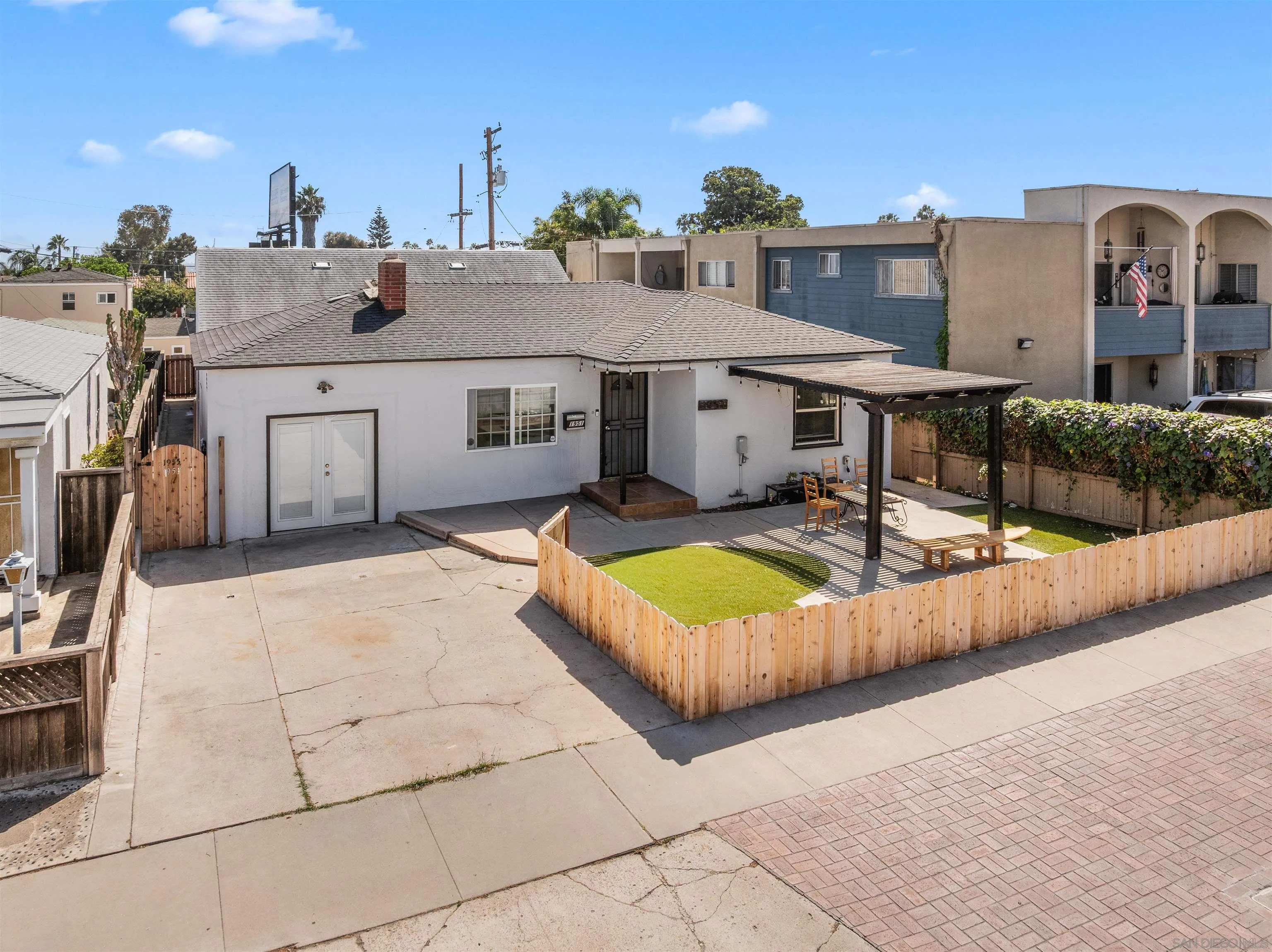 Rear exterior of a single-story home with a fenced lawn and covered patio.
