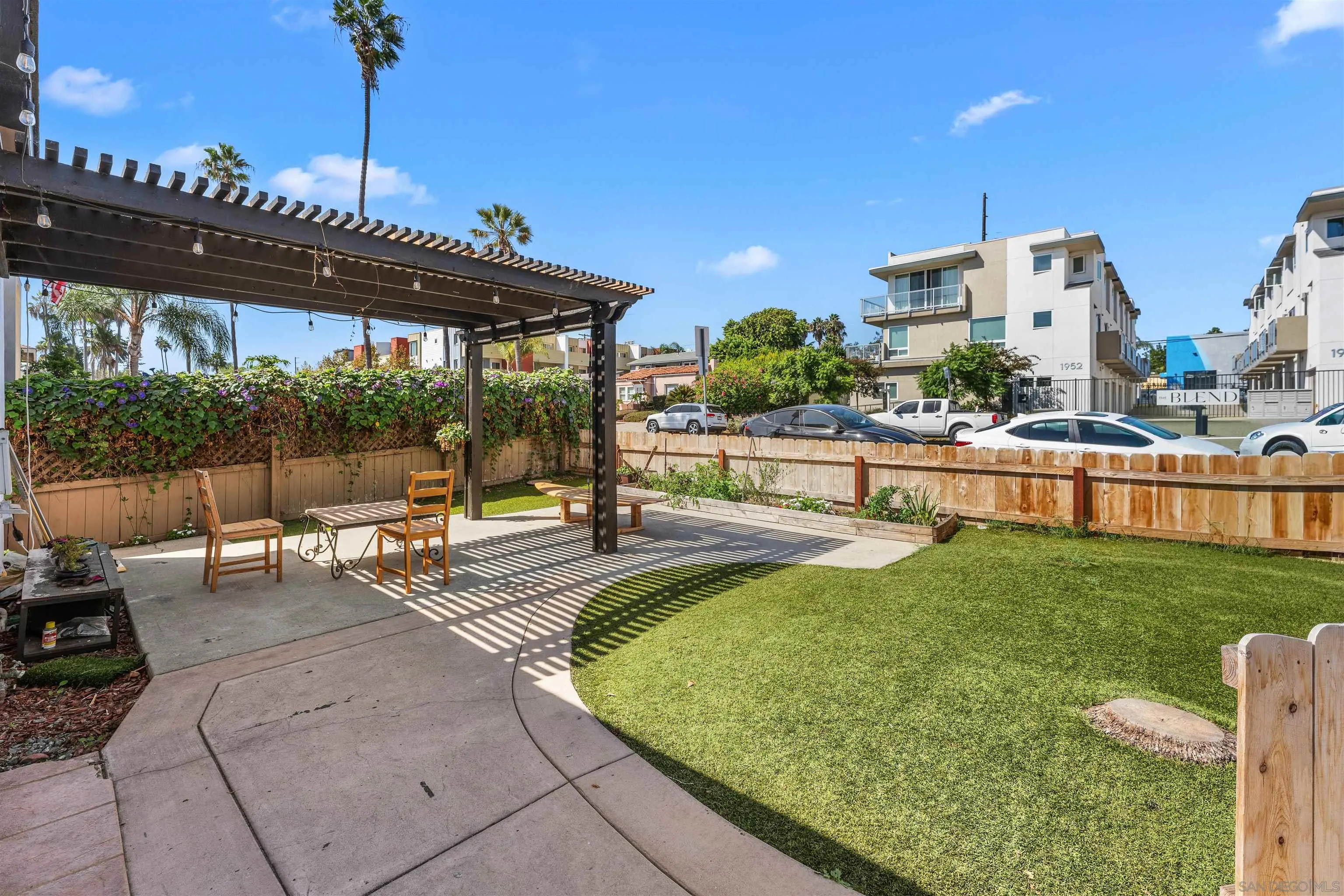 Landscaped outdoor patio with a pergola, seating, lawn, and fenced garden.