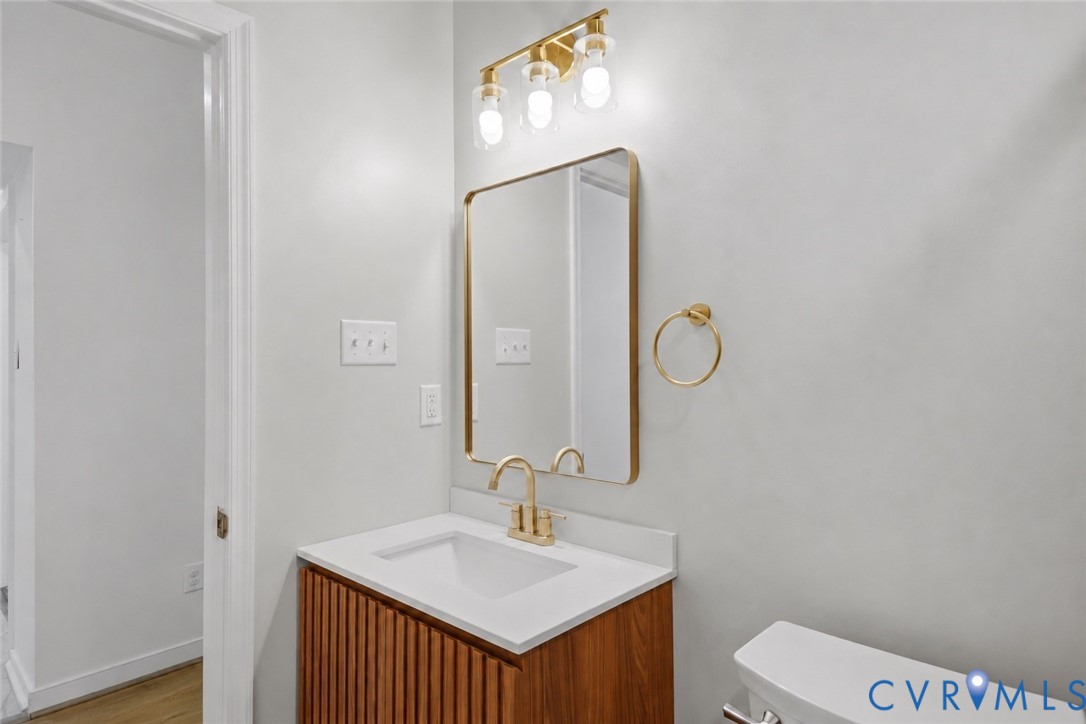 Bathroom vanity with a fluted wood cabinet, gold-framed mirror, and brass fixtures.