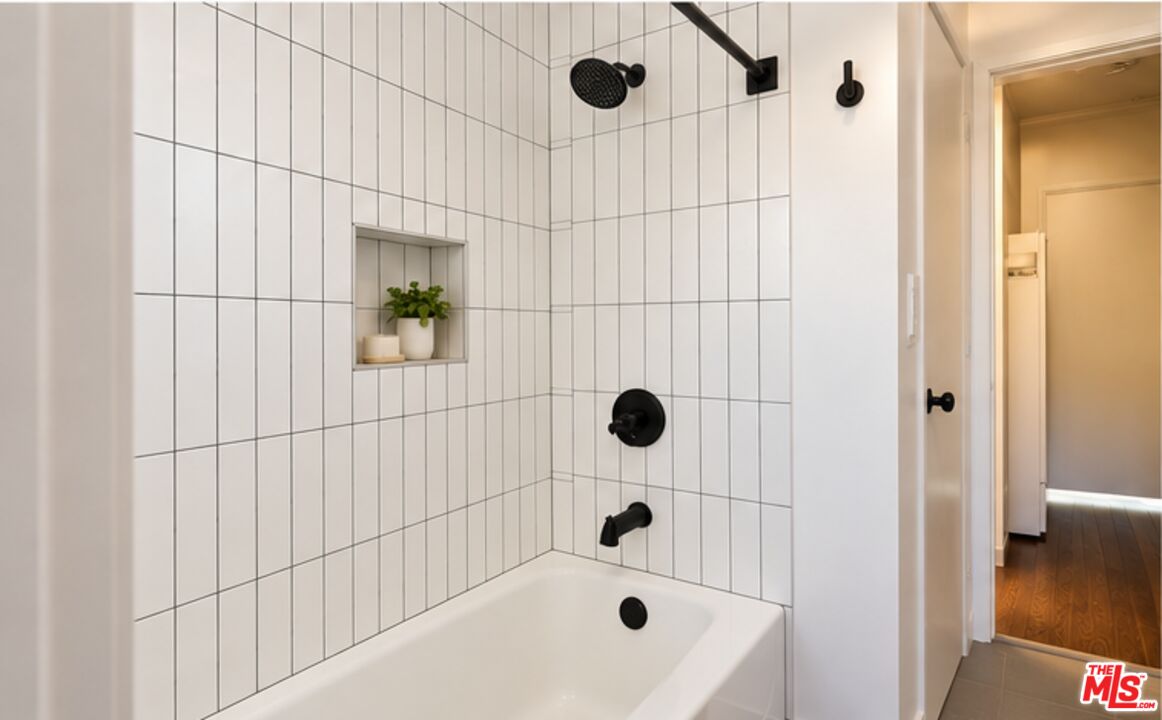 Bathroom with a white tiled shower, black fixtures, and a recessed niche holding a small plant.