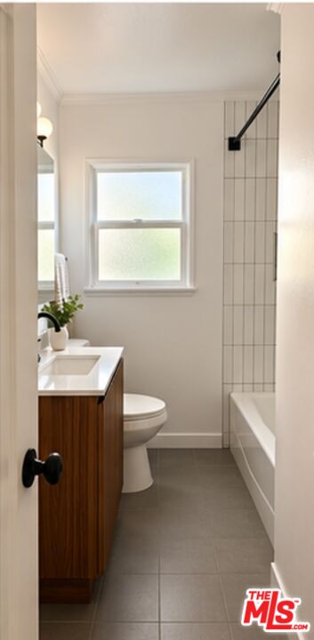 Bathroom with a wood vanity, toilet beneath a frosted window, and white tiled bathtub surround.