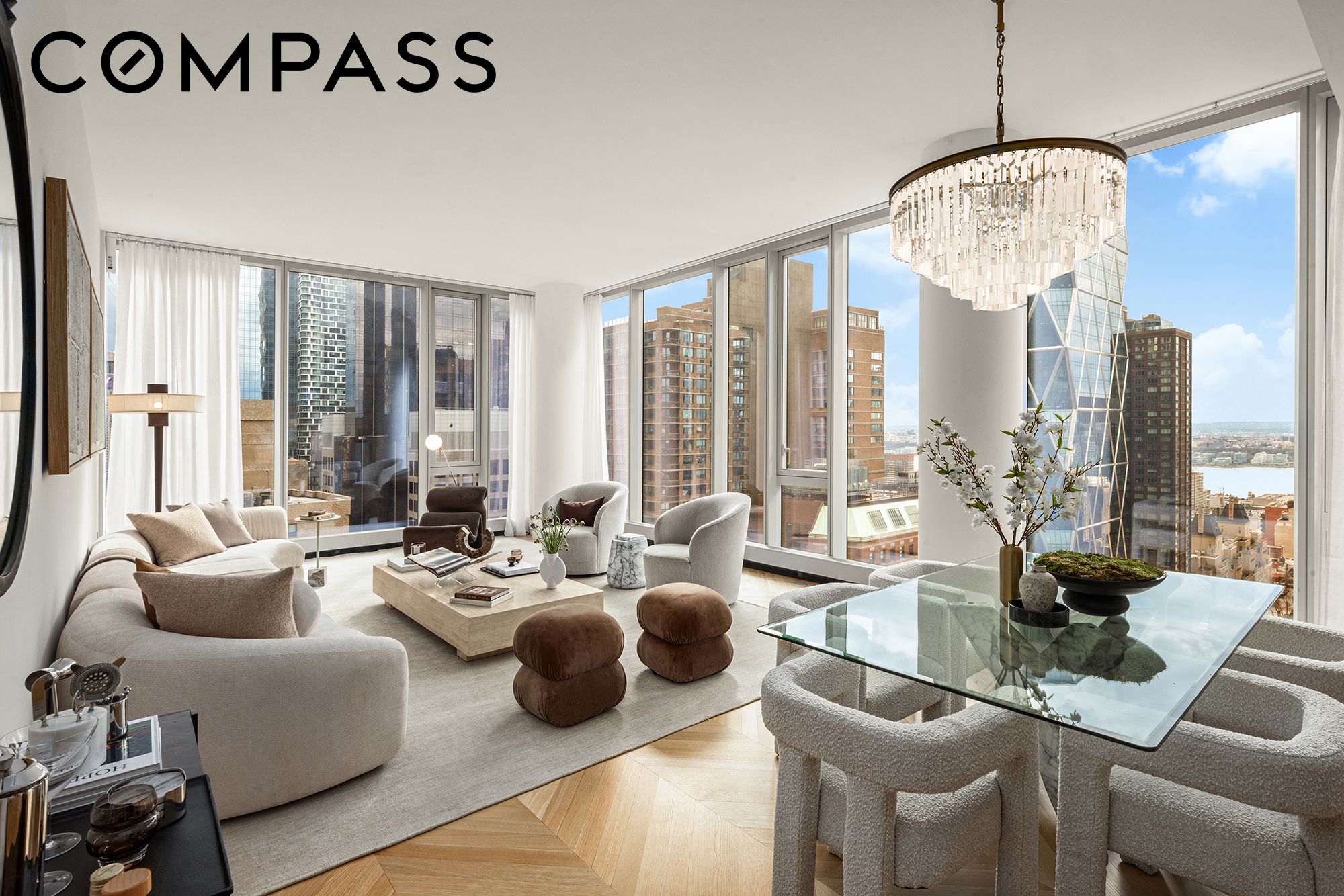 Furnished high-rise living and dining room with floor-to-ceiling windows and city views.
