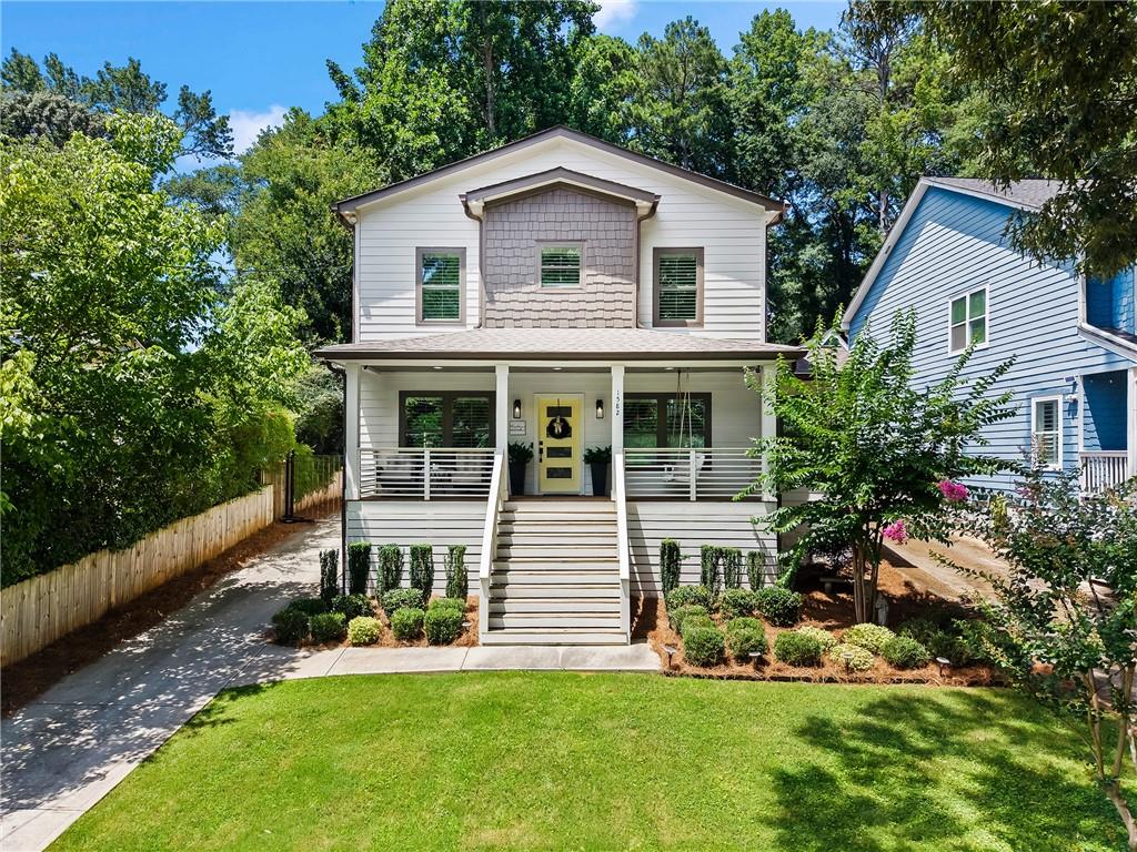Two-story white house with a covered porch, yellow front door, and landscaped lawn.