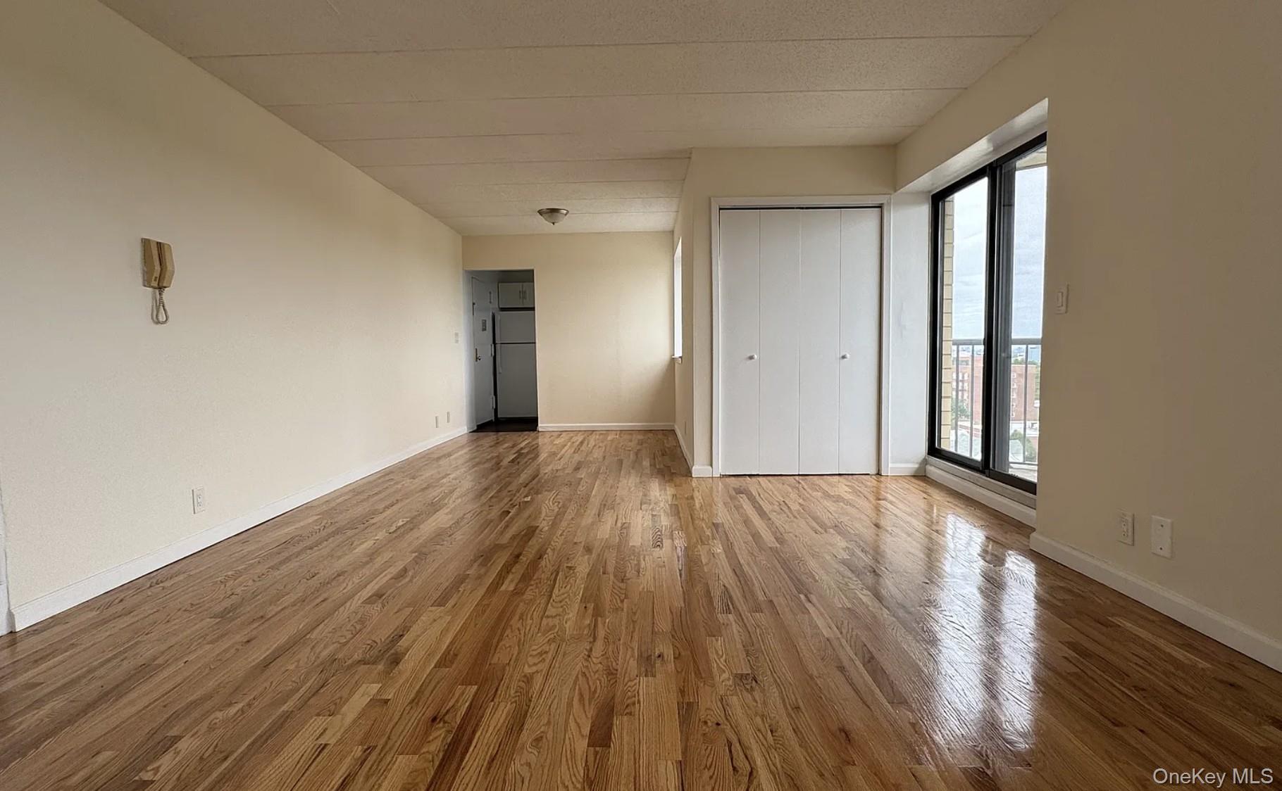 Vacant living room with hardwood floors, a closet, and sliding glass doors to a balcony.