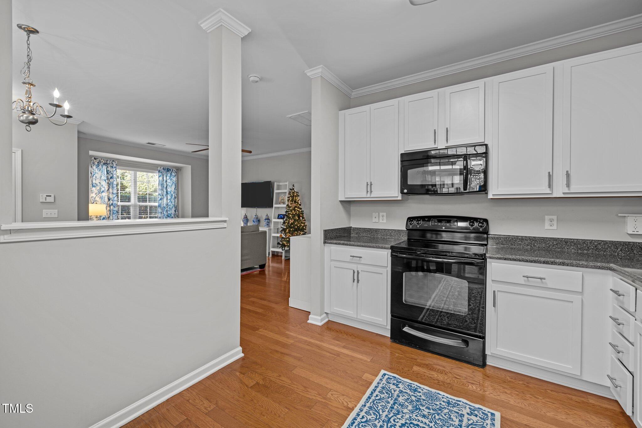 Kitchen with white cabinets, black appliances, granite counters, and a pass-through to the living area.