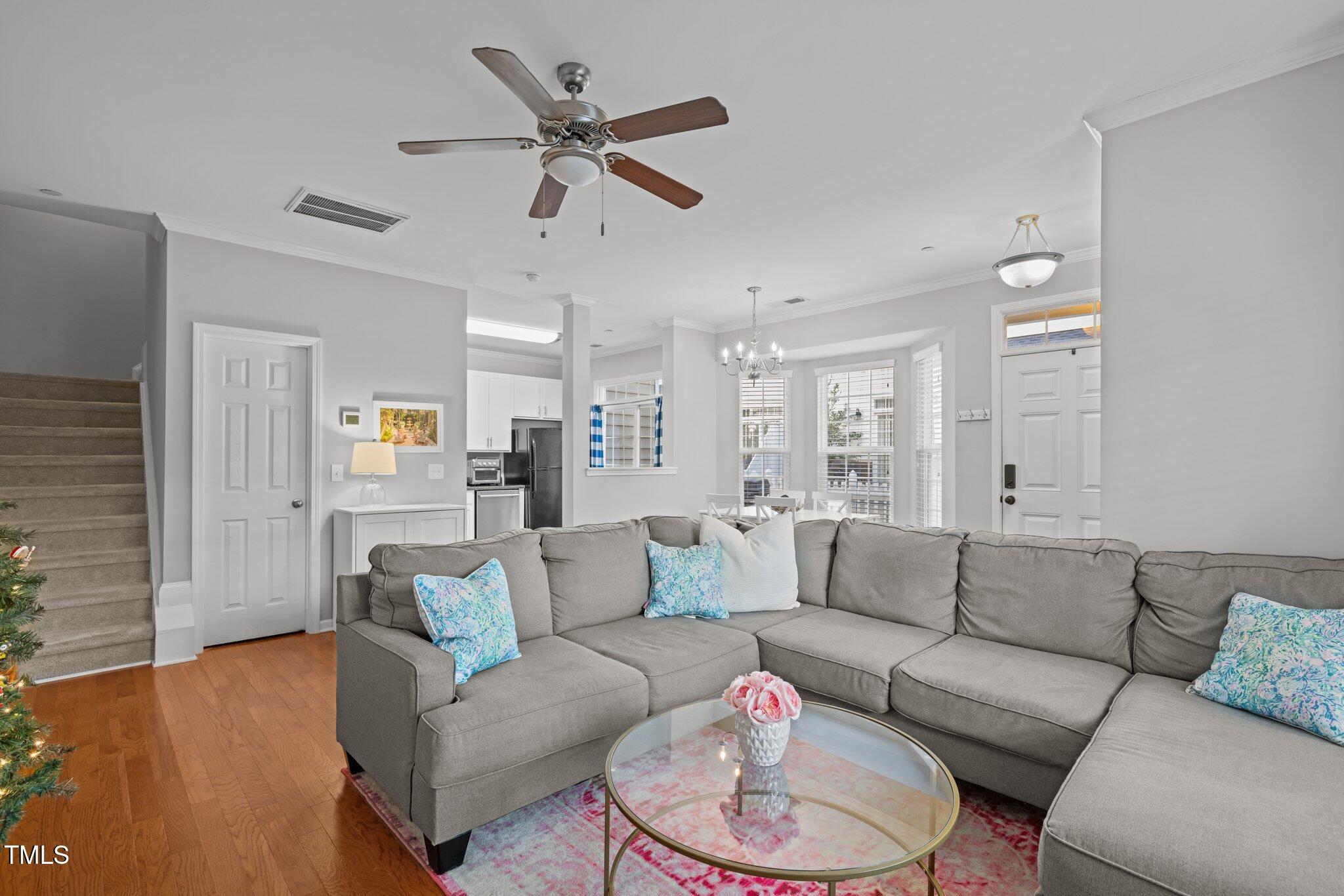 Furnished living room with a gray sectional, glass coffee table, and open kitchen and dining area.