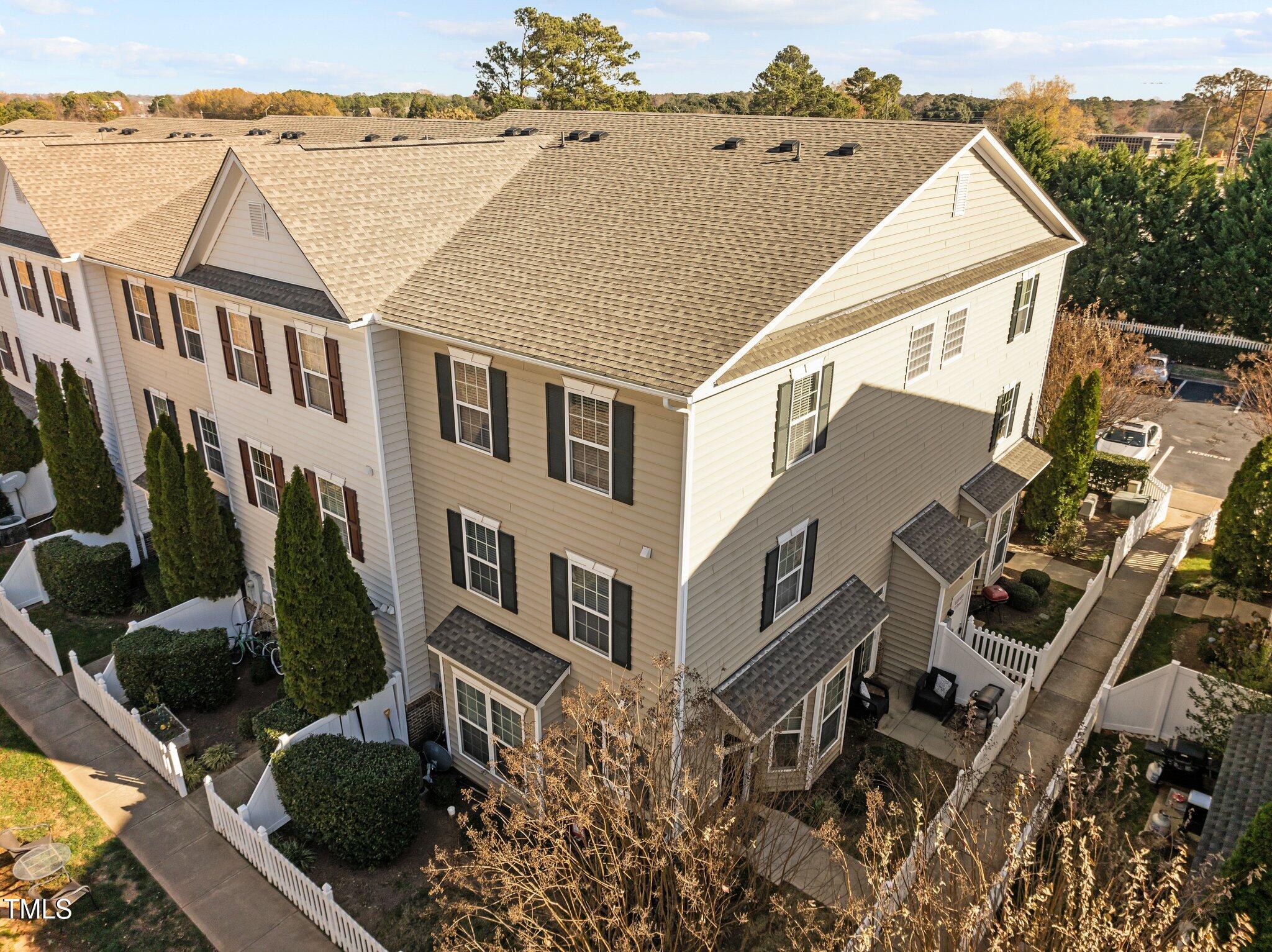Aerial view of a beige townhouse building with fenced patios and landscaped walkways.