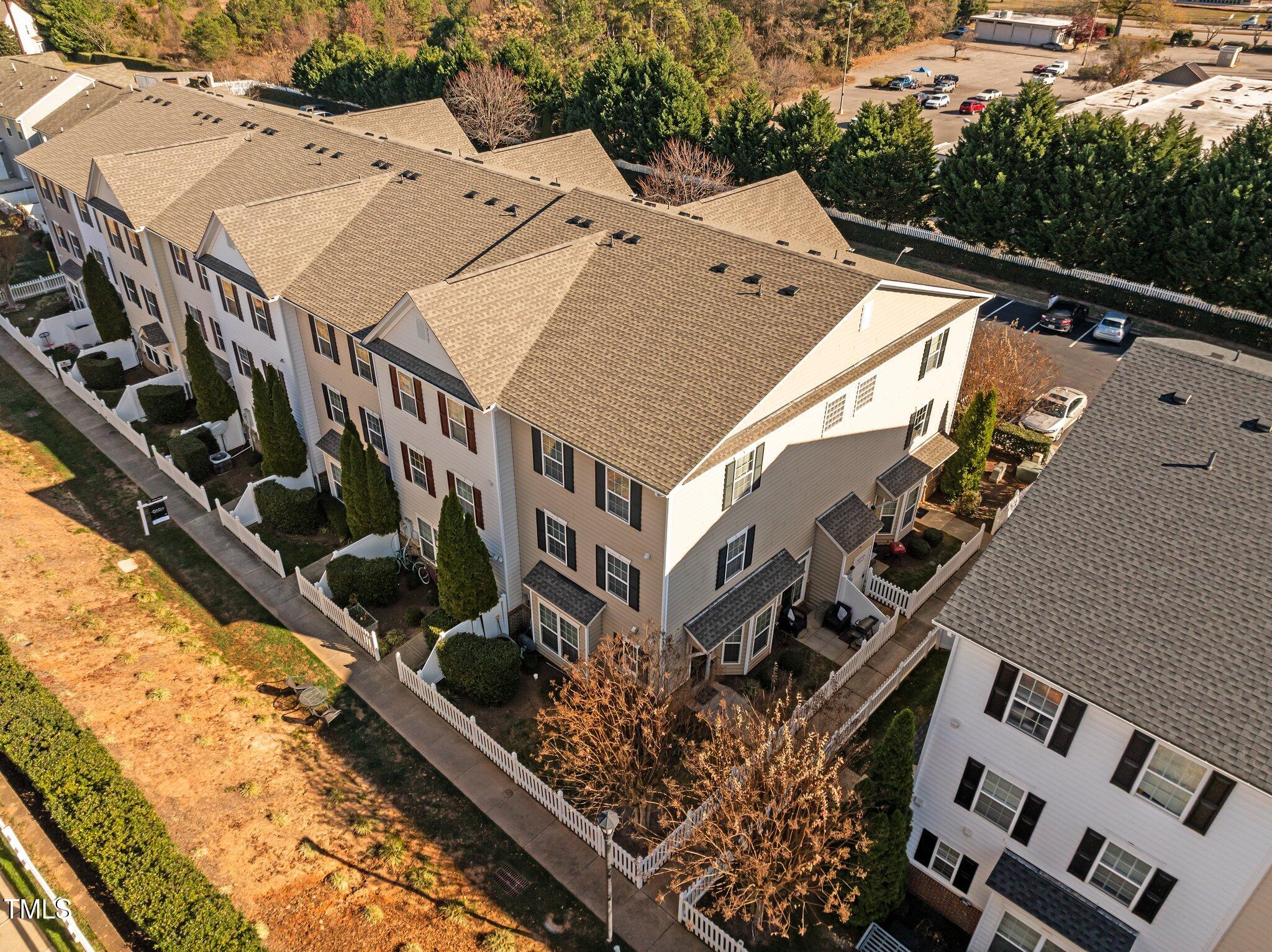 Aerial view of attached townhomes with white picket fences and a shared parking area.