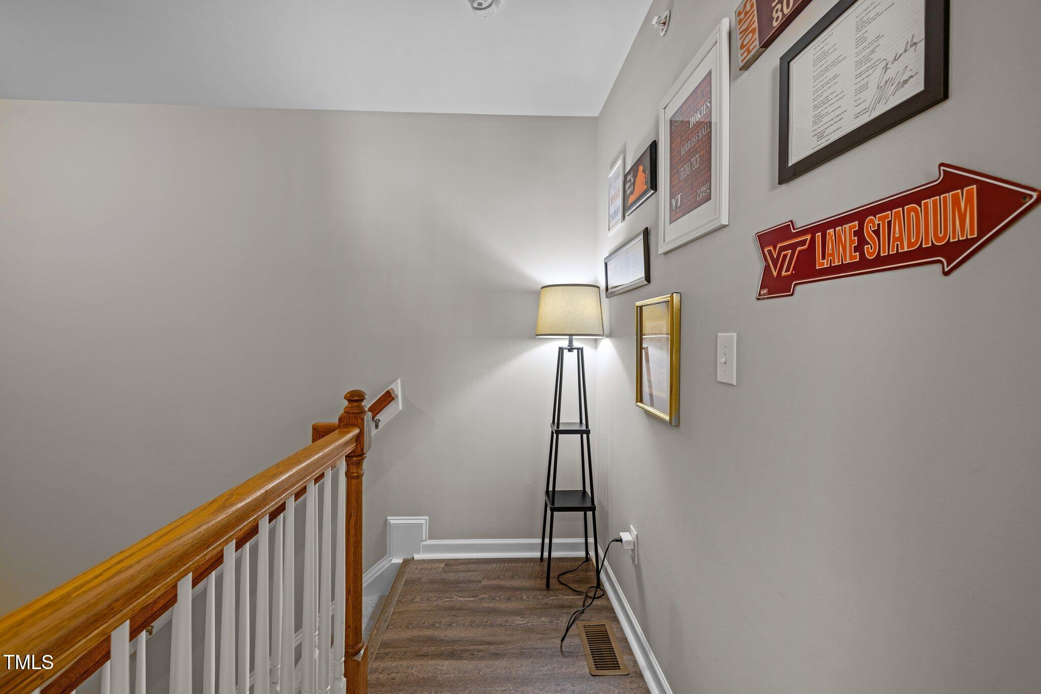 Stair landing with a wooden handrail, lit floor lamp, and Virginia Tech Lane Stadium sign.