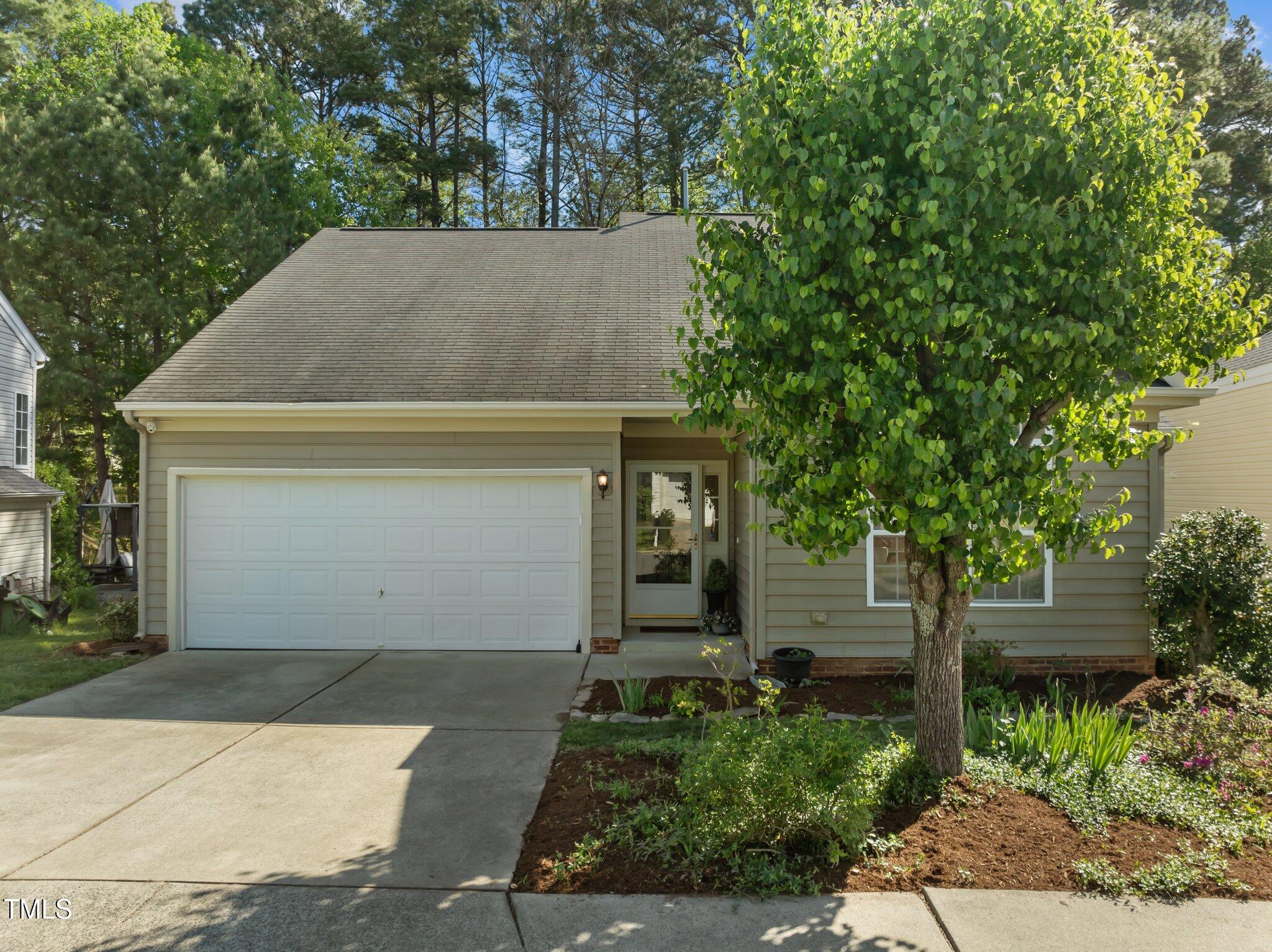 House exterior with a double garage, covered entry, and large leafy tree in front.