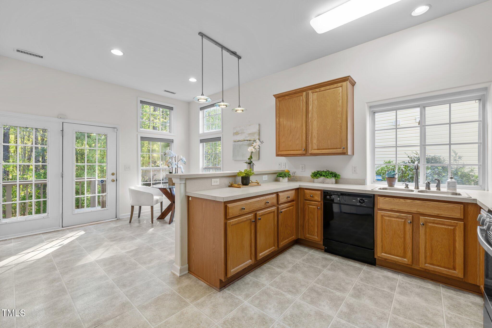 Bright kitchen with oak cabinets, gray tile floors, and a large window over the sink.