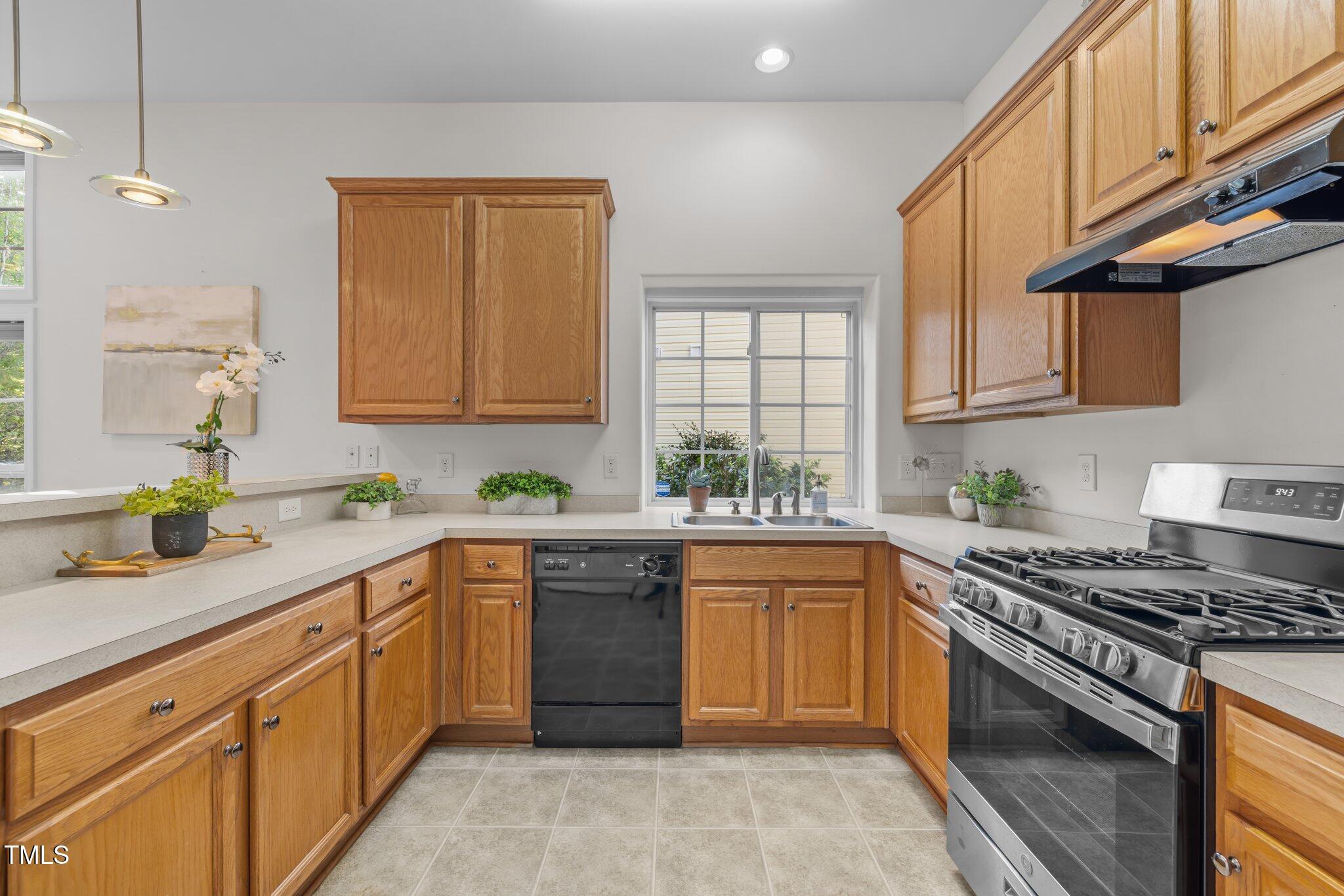 Kitchen with oak cabinets, stainless steel gas range, and sink beneath a window.