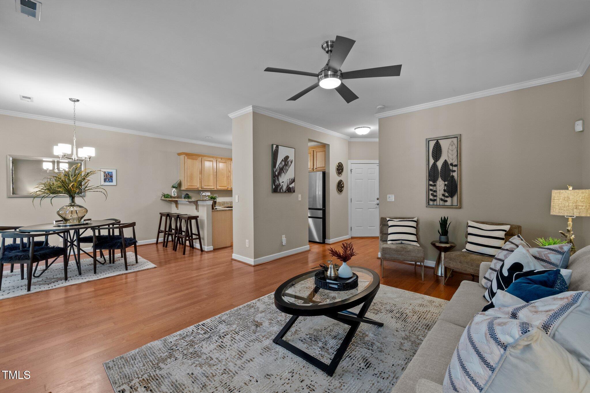 Open-plan living and dining area with hardwood floors, a ceiling fan, and an adjoining kitchen.