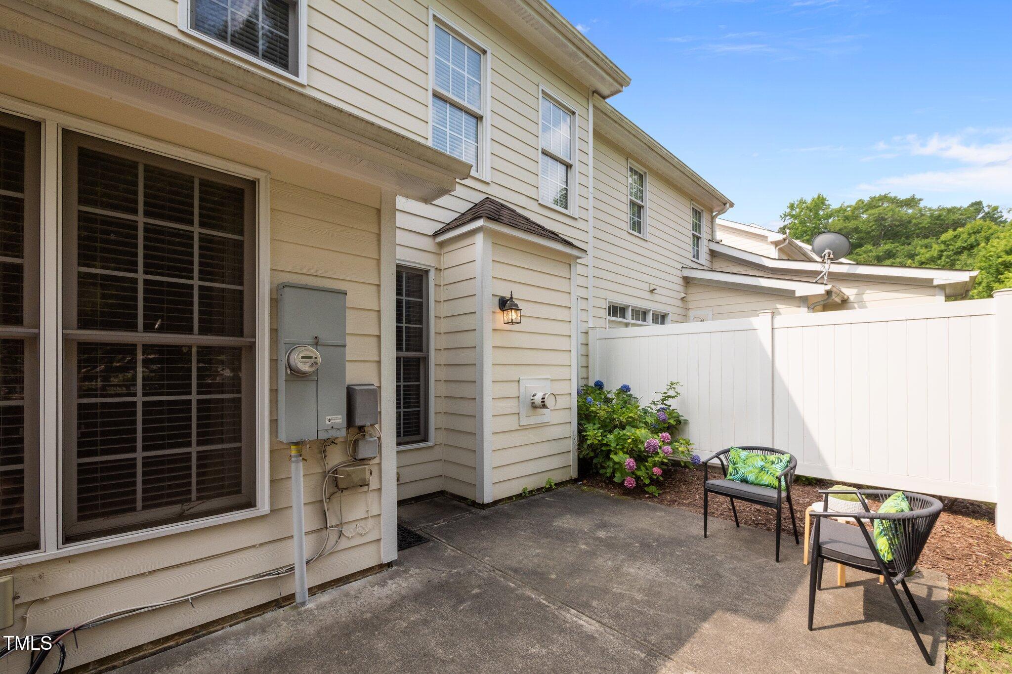 Townhouse patio with two chairs, a white privacy fence, and flowering hydrangeas.