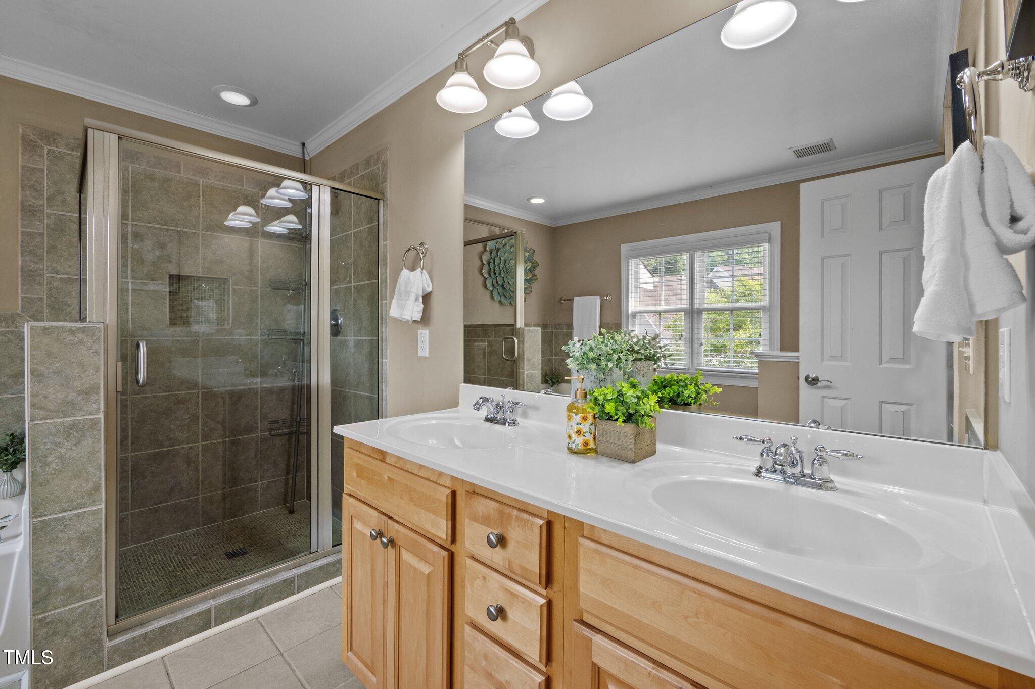 Bathroom with a tiled glass shower and long double-sink wood vanity.