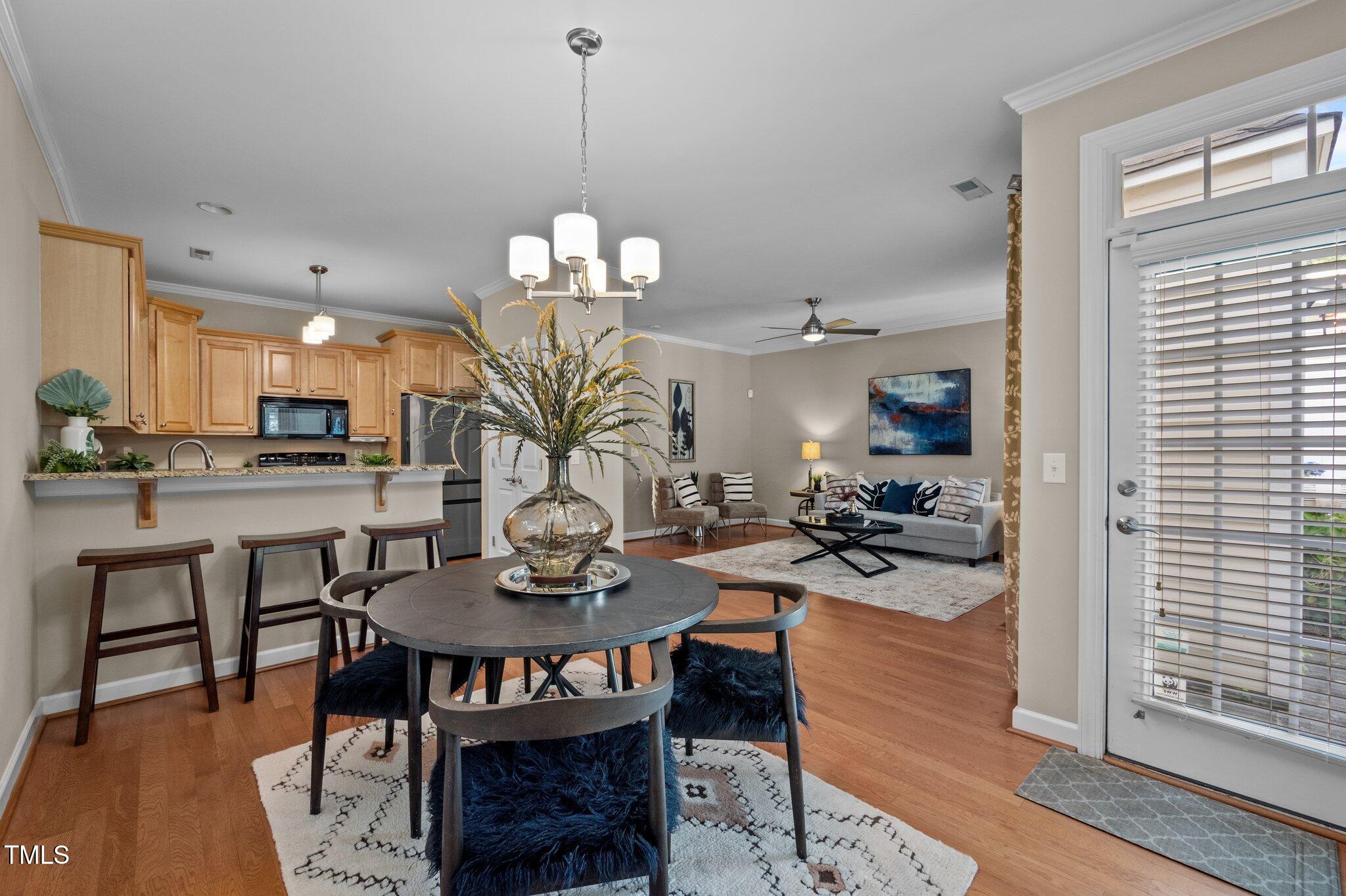 Open-plan dining area with a round table, wood-cabinet kitchen, and living room with gray sofa.