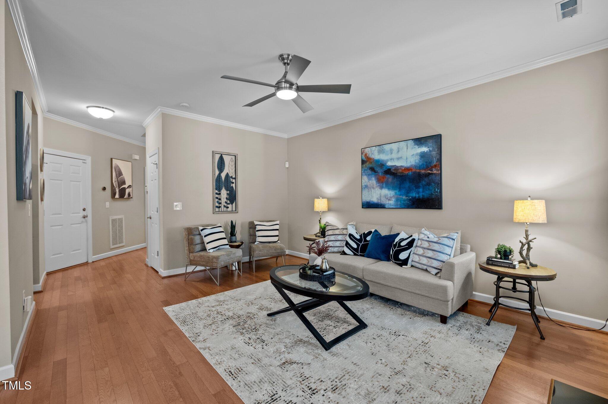 Furnished living room with hardwood floors, a light sofa, accent chairs, and a black oval coffee table.