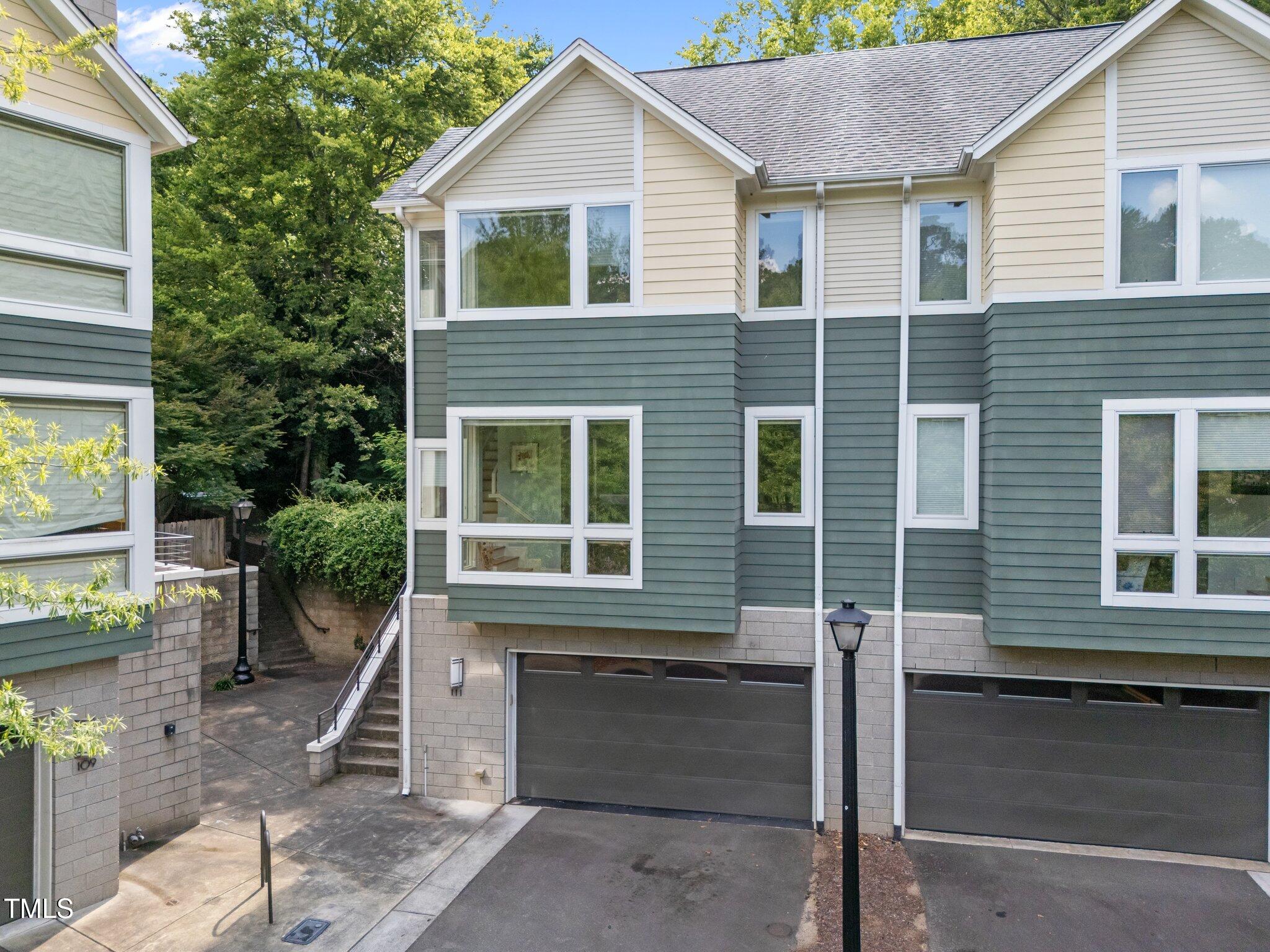 Townhouse exterior with gray garages, cream siding, and a stairway between buildings.