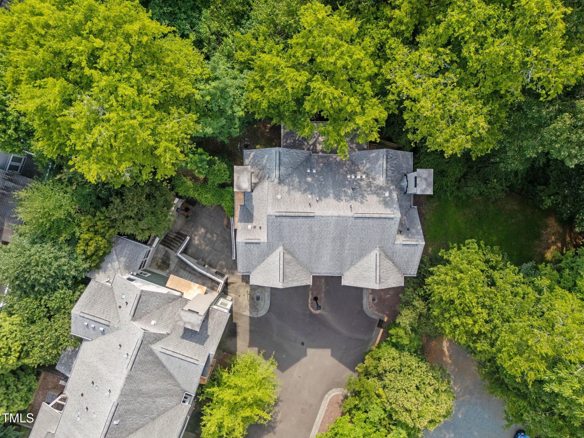 Aerial view of gray-shingled buildings surrounded by trees and paved parking areas.