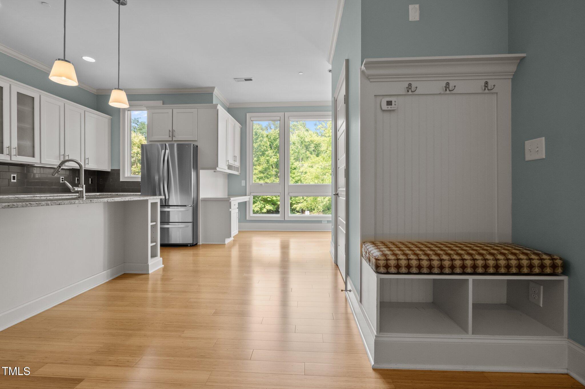 Kitchen with white cabinets, stainless steel refrigerator, and a built-in window-side bench.