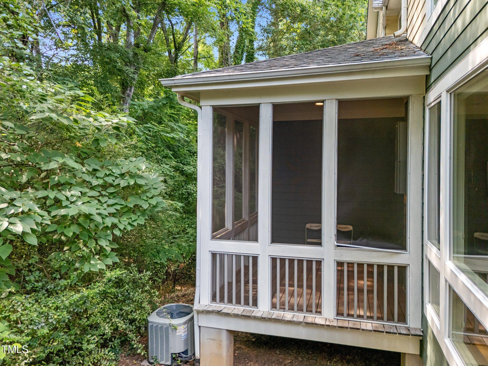 Screened porch with white framing and a wooded backdrop.