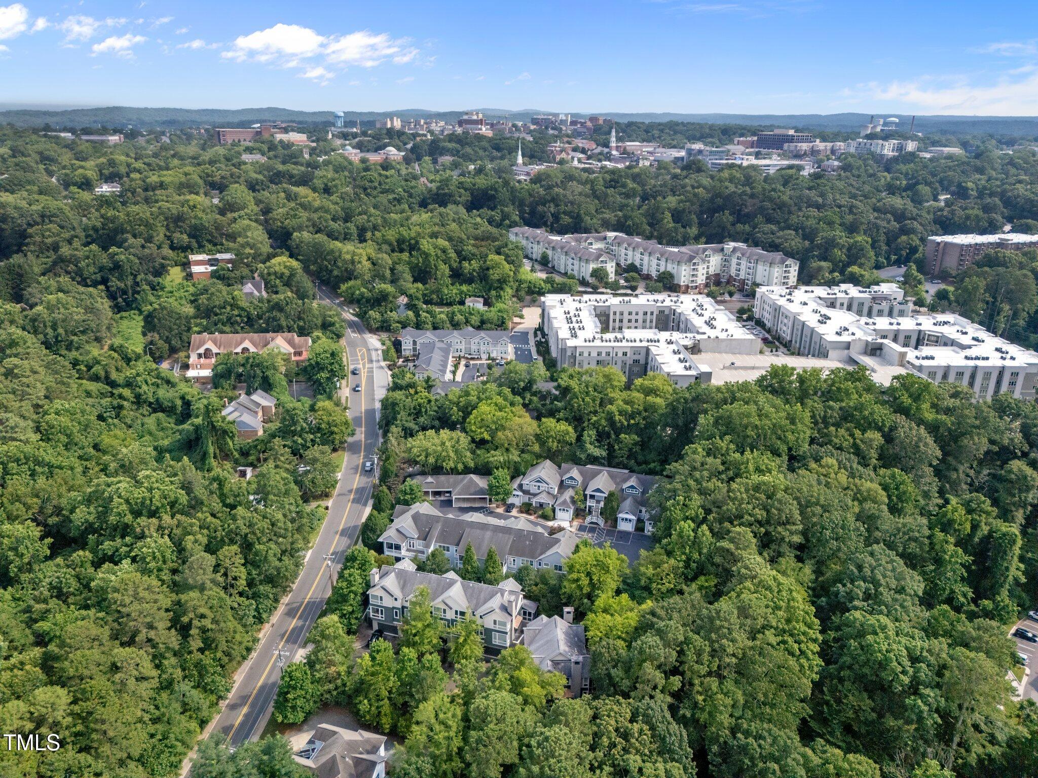 Aerial view of a leafy neighborhood with apartment complexes, homes, and a road.