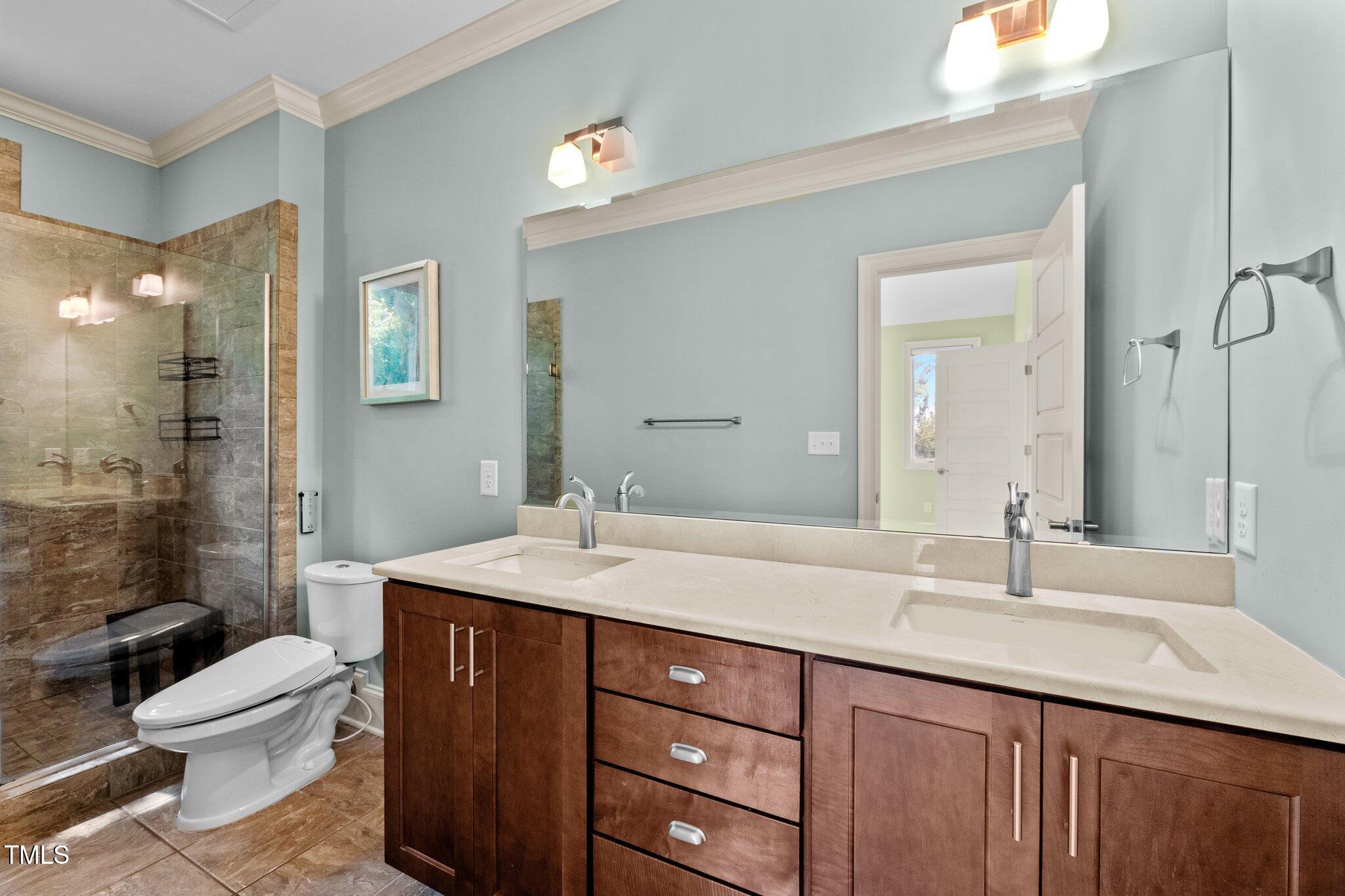 Bathroom with a double-sink vanity and a glass shower featuring a tiled bench.