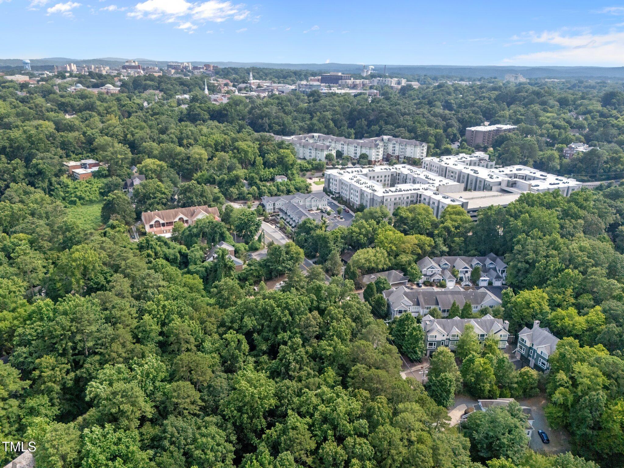 Aerial view of a wooded neighborhood with apartment buildings and townhomes.