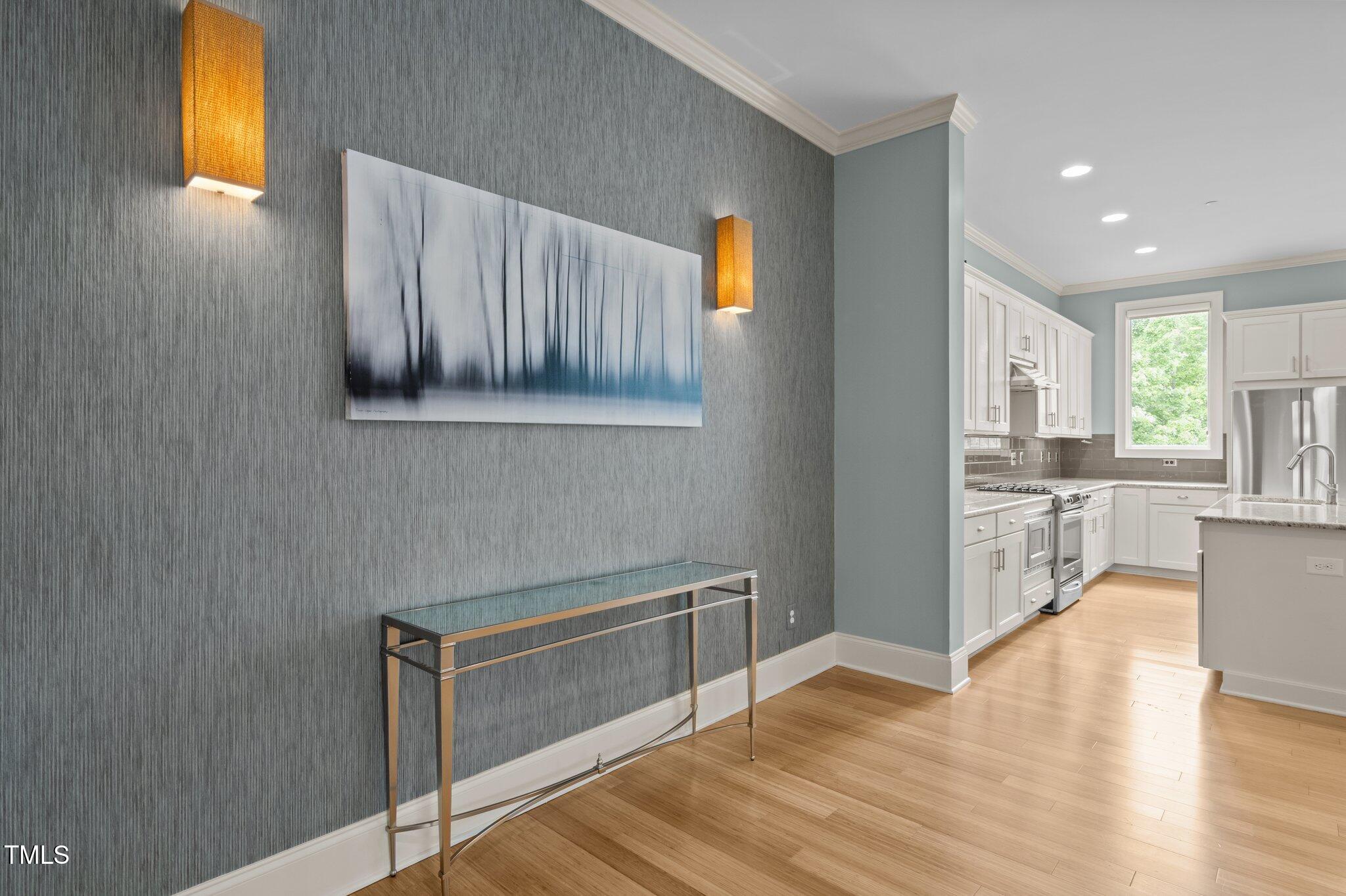Condo entryway with a gray accent wall and console table opening into a bright white kitchen.