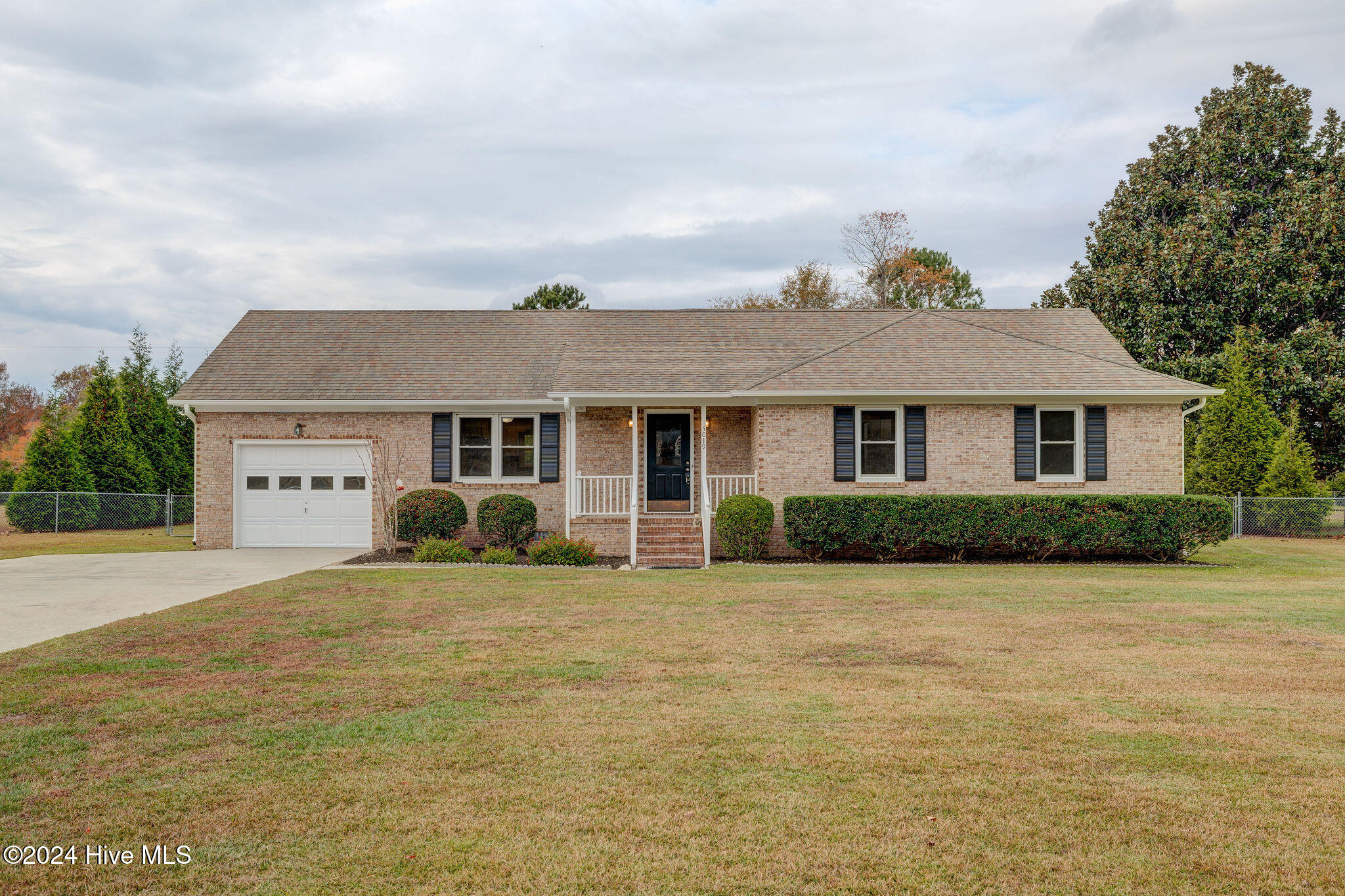 Single-story brick ranch with an attached garage, covered entry porch, and broad front lawn.