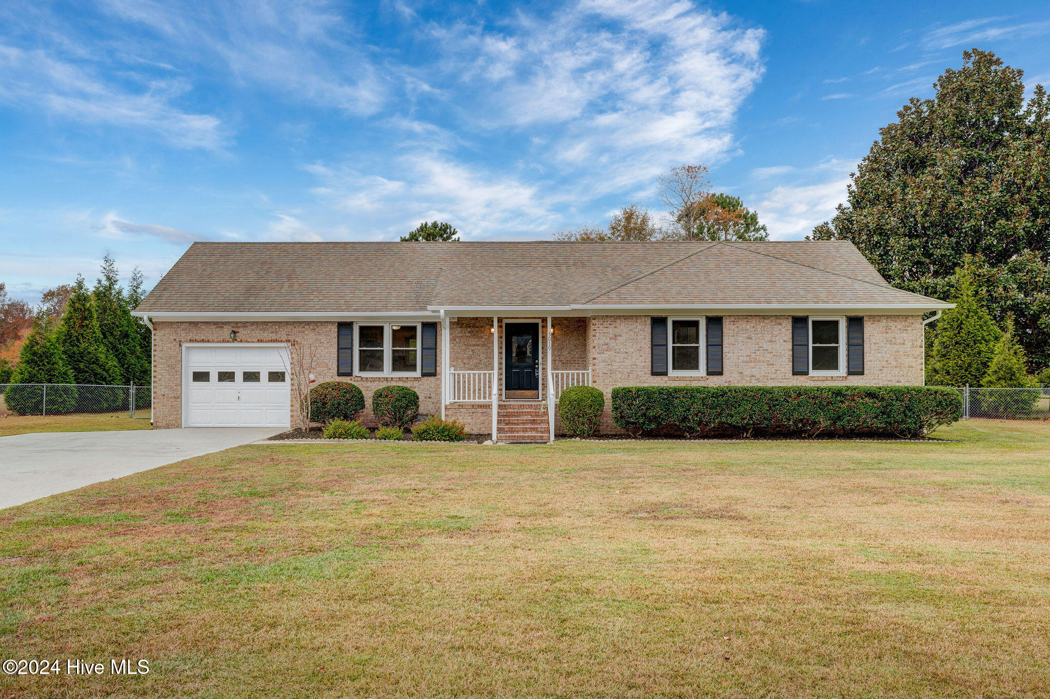 Single-story brick home with a white garage, black shutters, and a covered front entry.