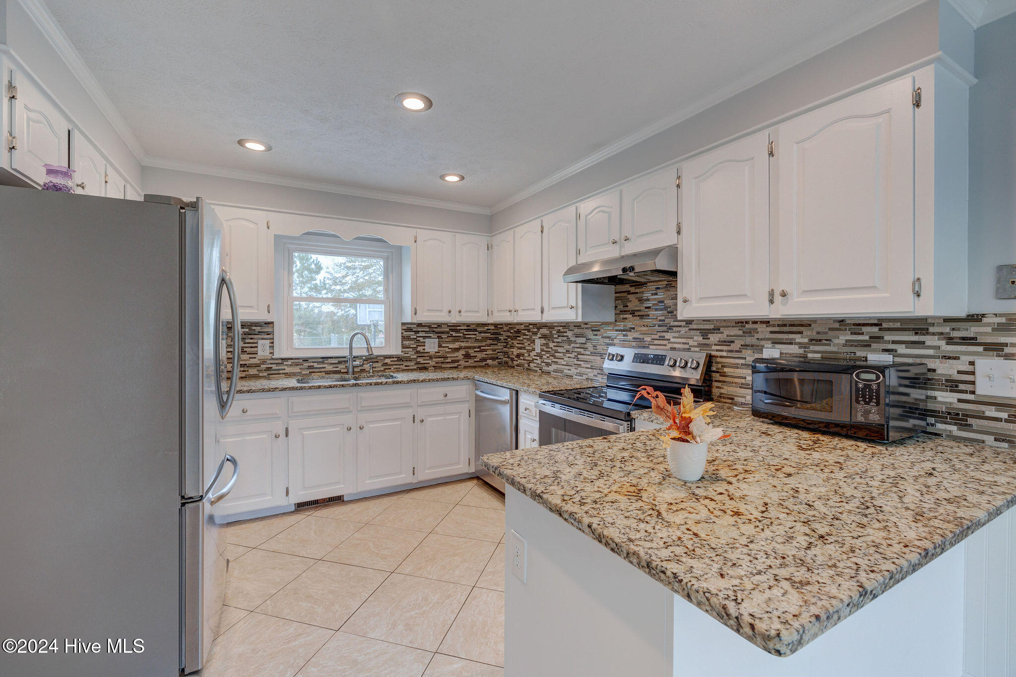 Kitchen with white cabinets, granite counters, stainless steel appliances, and a large peninsula.